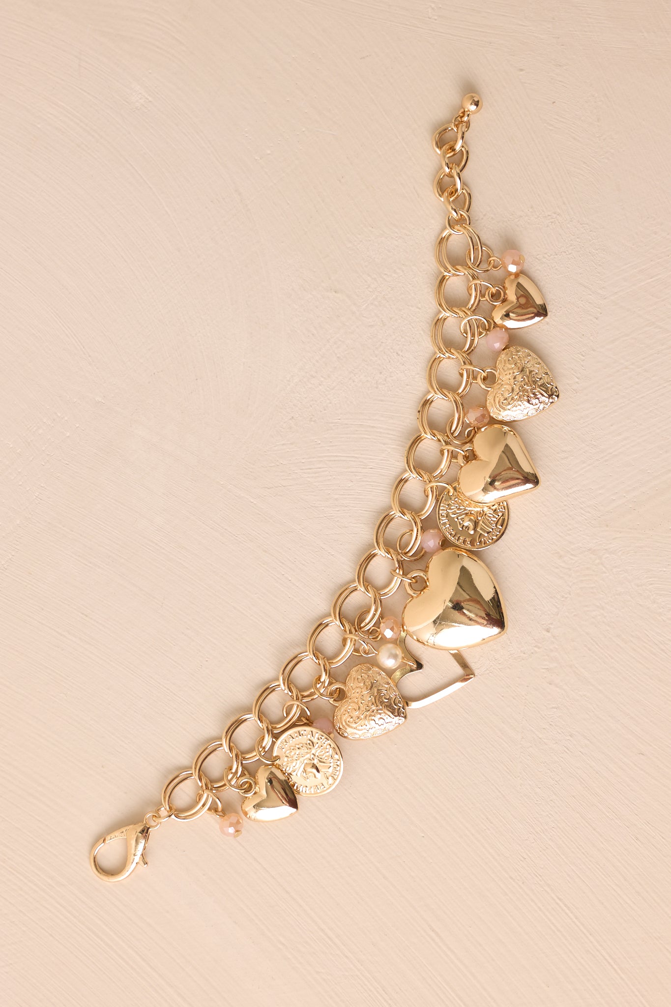 A detailed angle of the bracelet showcasing the gold jump rings, small pink accent beading, and intricate charm designs.