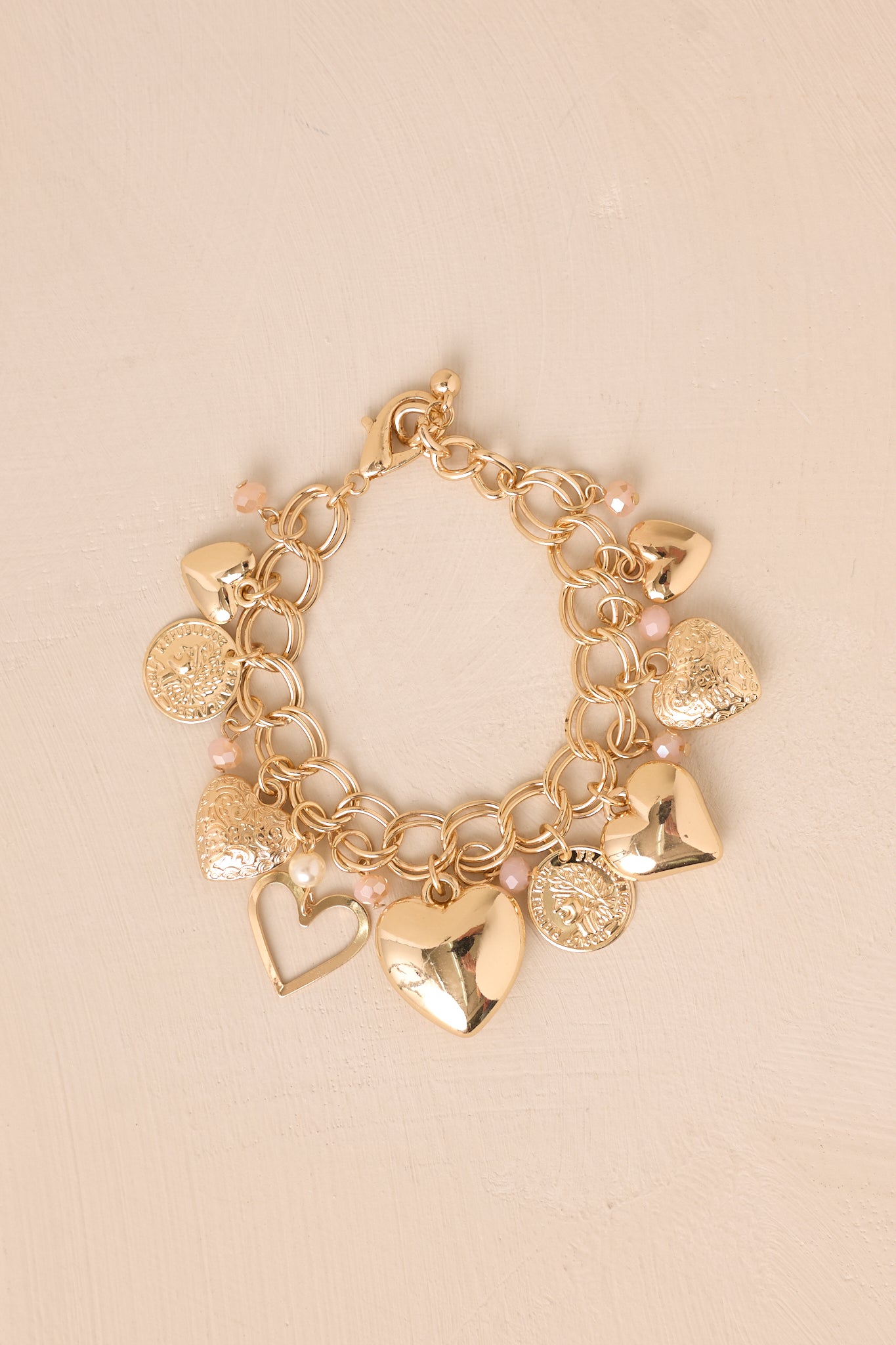 A zoomed-in shot focusing on the bracelet’s lobster claw closure and the fine details of the heart charms and gold hardware.