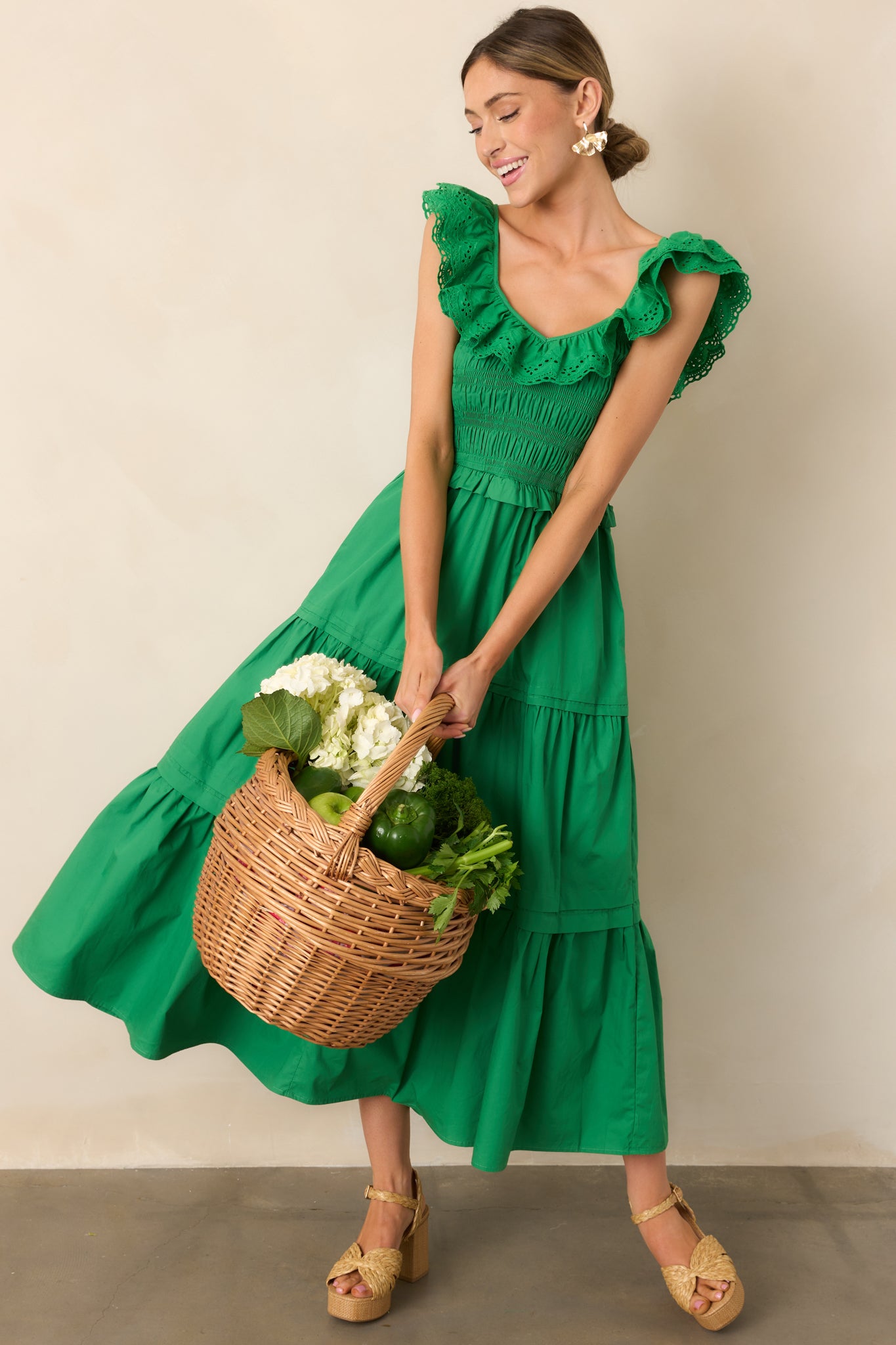 A graceful green maxi dress featuring a ruffled V-neckline, smocked bodice, and a tiered skirt, offering a blend of elegance and ease.