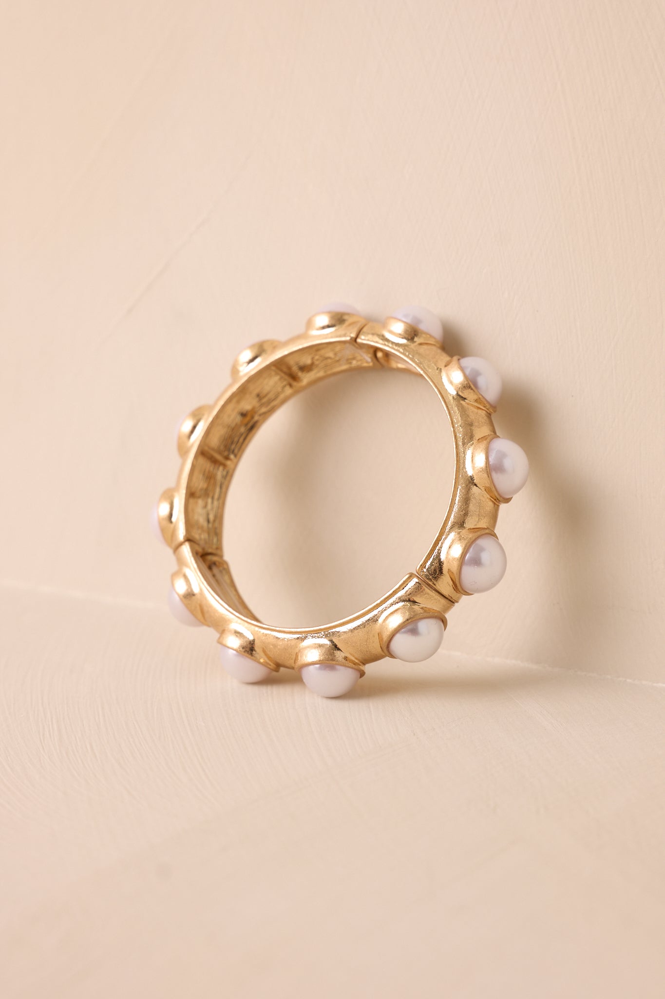 A detailed close-up of the bracelet, emphasizing the texture of the pearls, gold hardware, and intricate design elements.