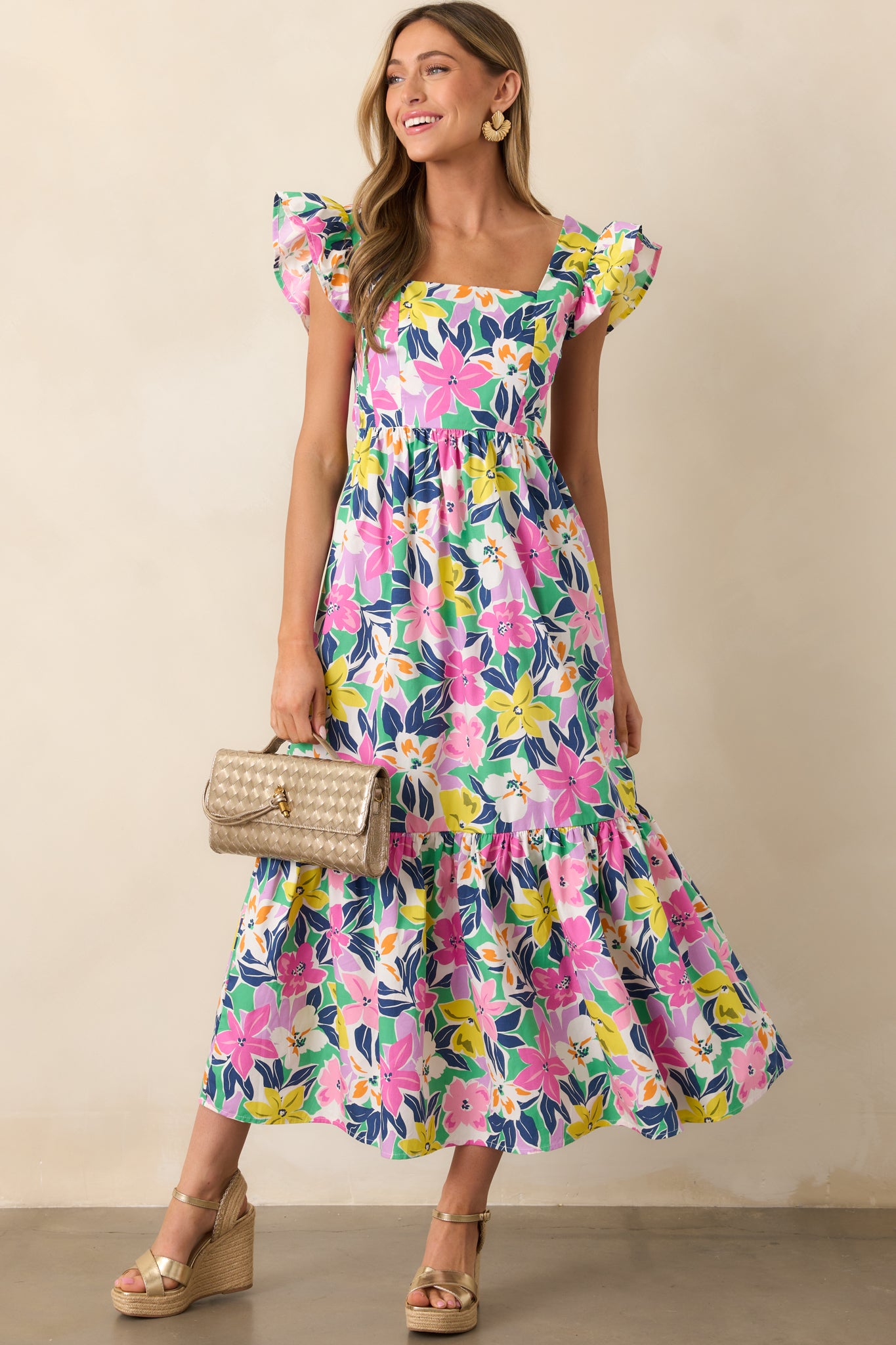 A pink maxi dress with a straight neckline, flutter sleeves, and a relaxed skirt, shown in full length from the front, highlighting the tropical floral print.