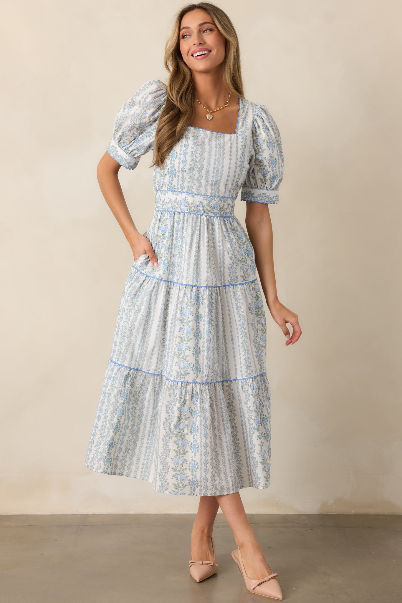 A front-facing view of the blue midi dress, showcasing its square neckline, puff sleeves, and floral print.