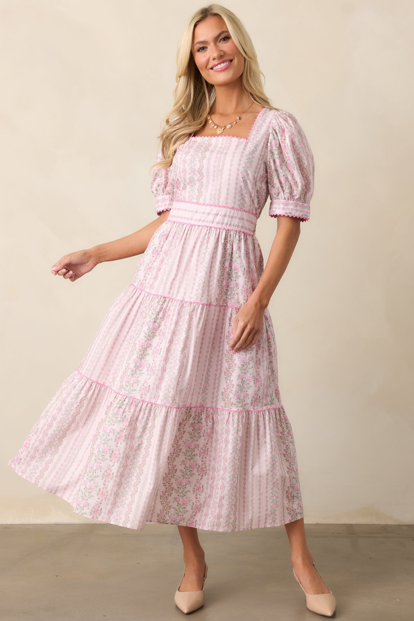 A slightly angled front view highlighting the flowy silhouette and midi length of the pink dress.