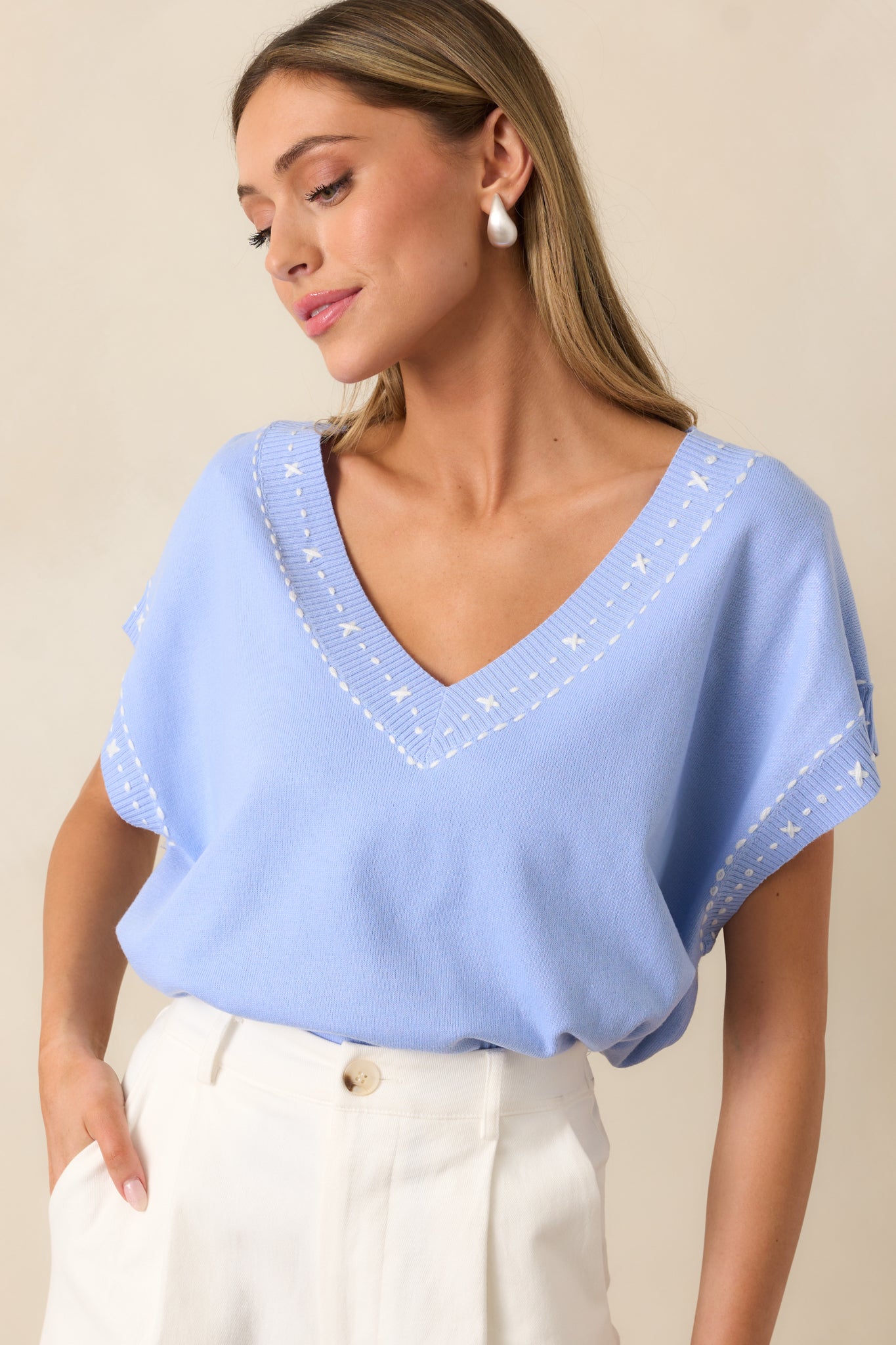 The relaxed fit and batwing sleeves create an airy, effortless drape, complemented by delicate white embroidery.