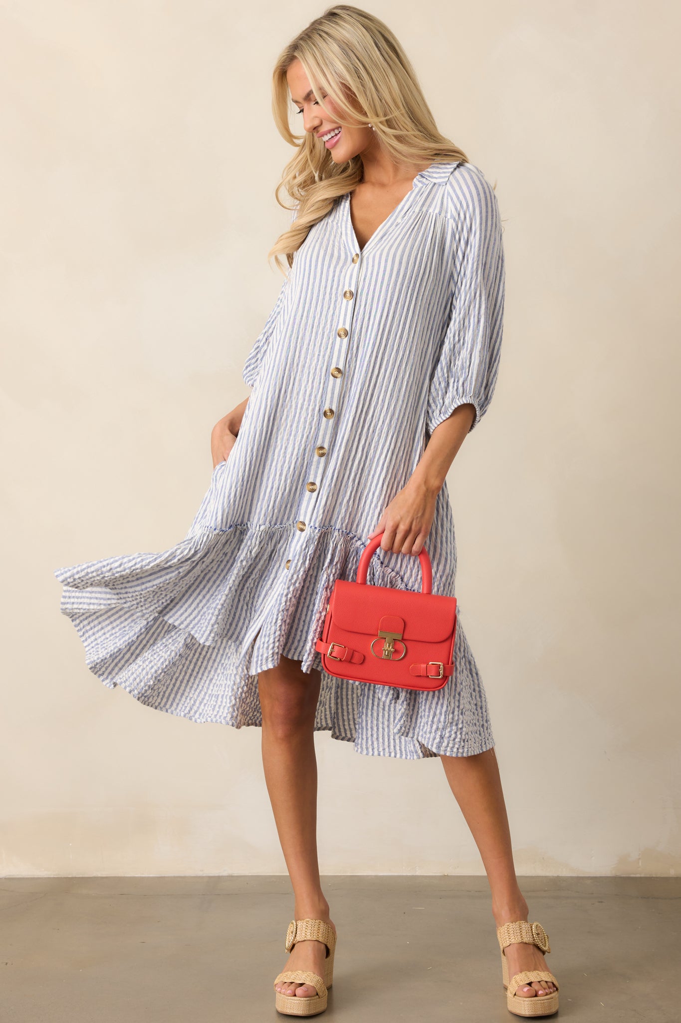 The blue mini dress’s hemline flows gently, enhancing the airy feel of the drop waist design.