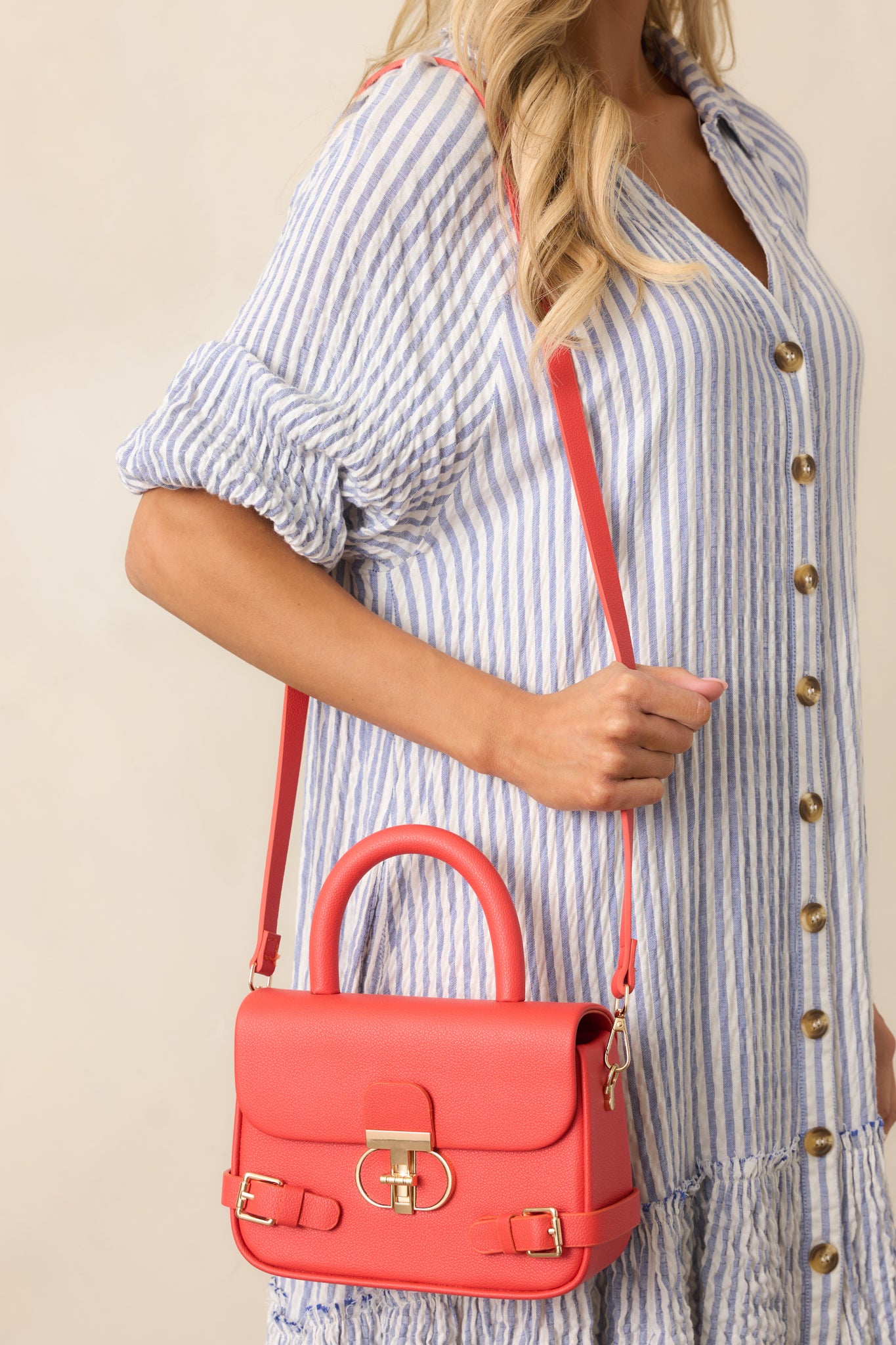 A side view of the handbag showing the gold buckle decor, solid red handle, and optional red shoulder strap.