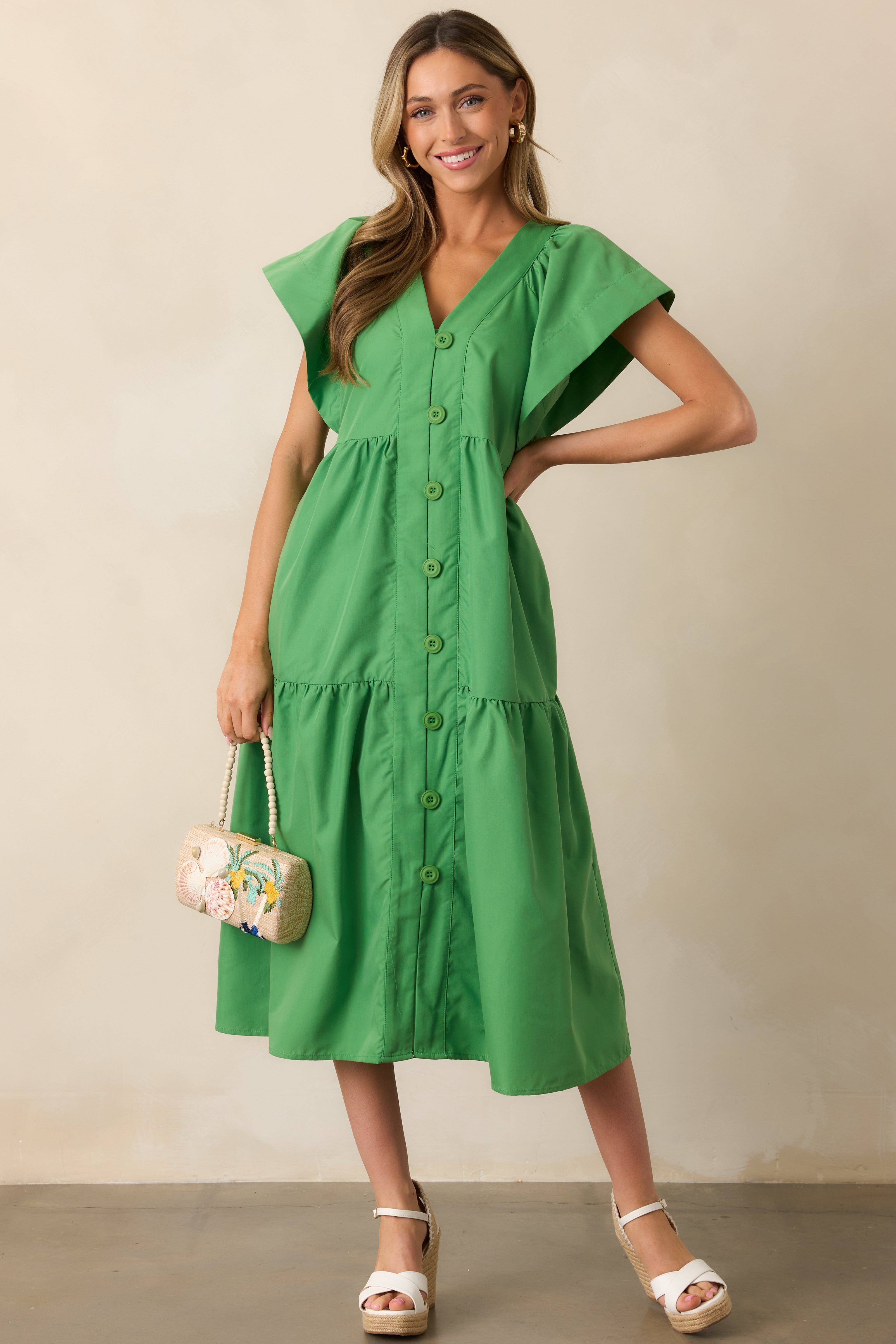 A front view of the green midi dress highlighting the v-neckline, button front design, and tiered skirt.