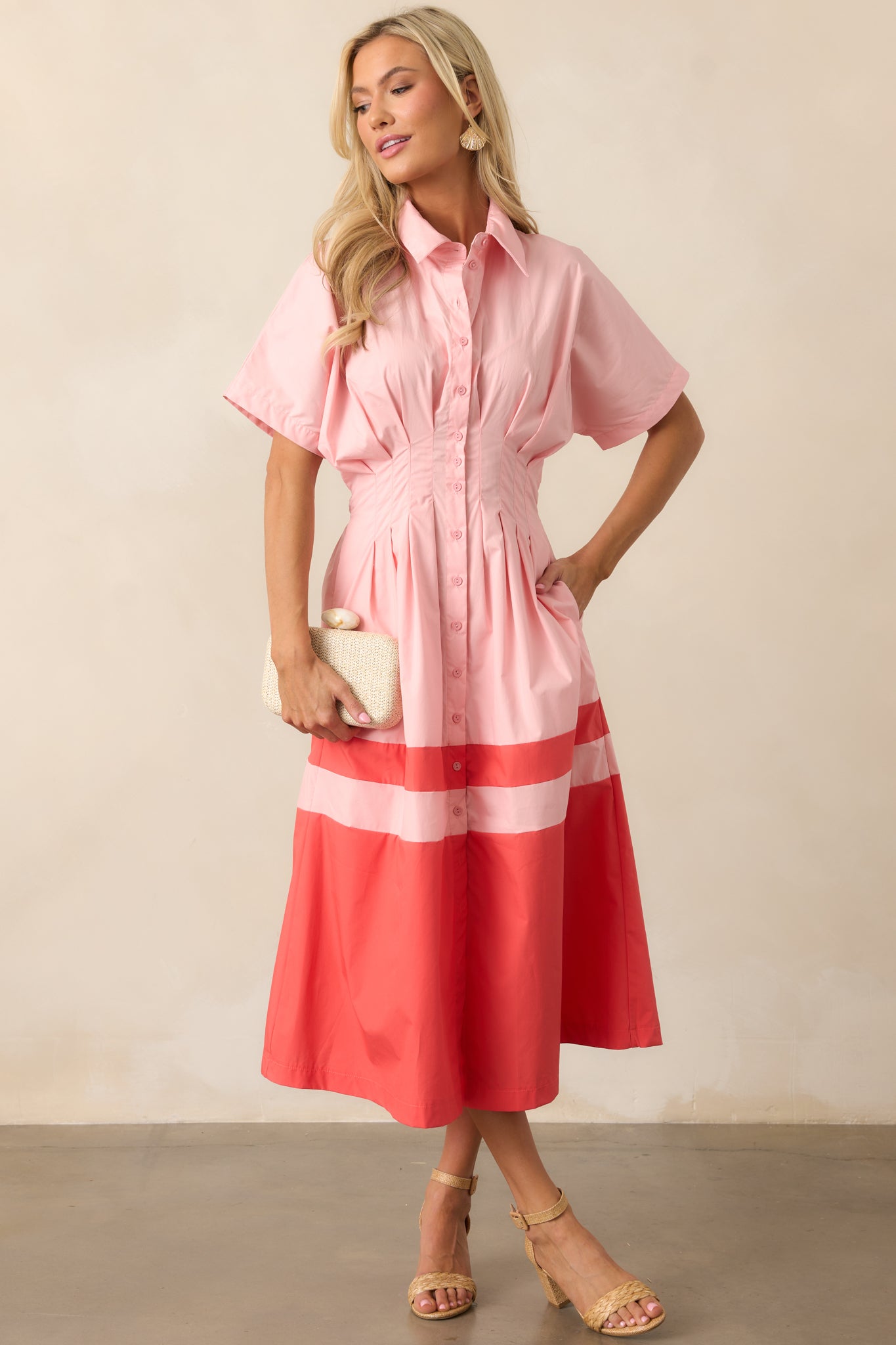 The pink midi dress from the front, emphasizing the short sleeves and coral color block skirt detail.