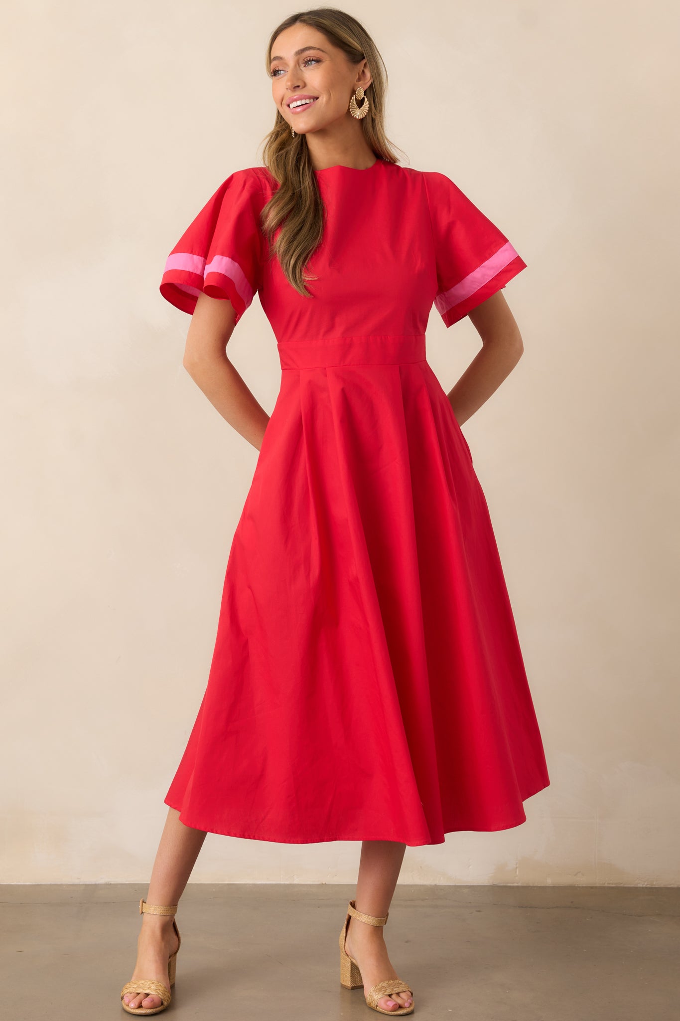 A red dress with a round neckline, puffy sleeves with pink stripe accents along the cuffs, and a fitted waistline for a flattering silhouette.