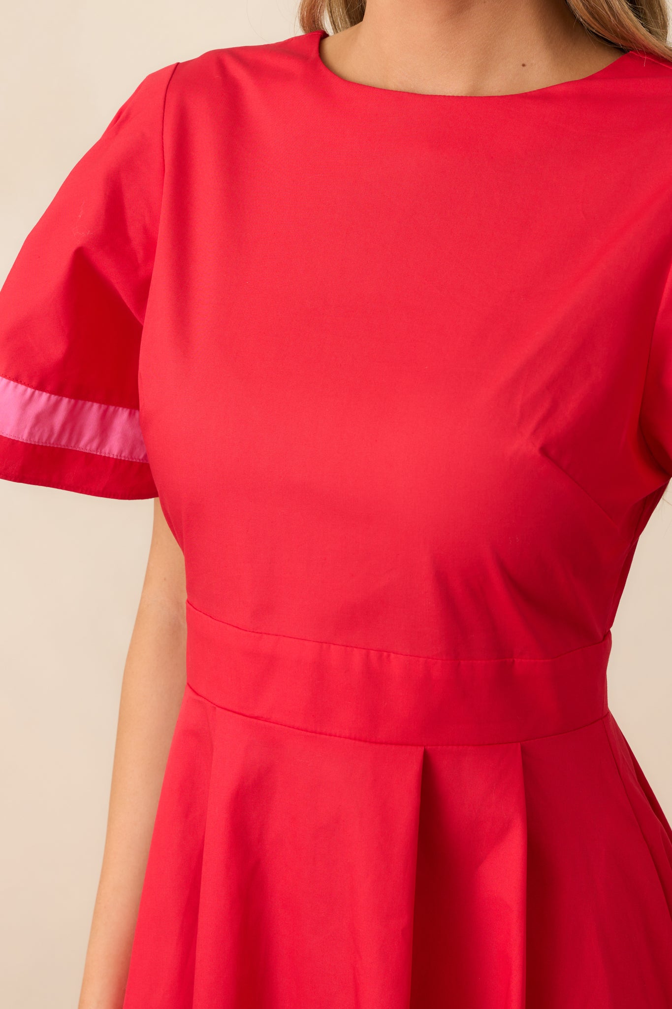 A close-up of the puffy sleeve with pink stripes along the cuffs, adding a pop of color and charm to the red dress.