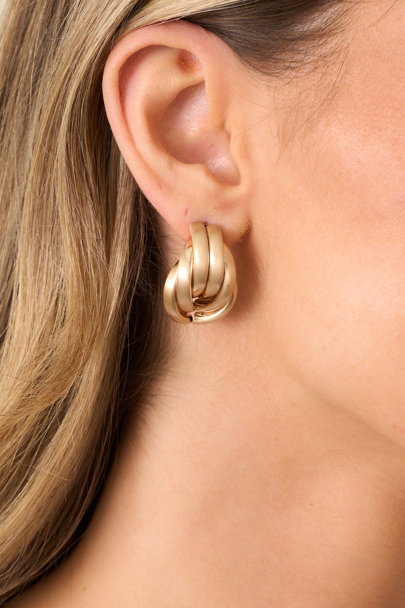 A zoomed-in shot focusing on the secure post backing and the smooth matte gold texture of the earrings.