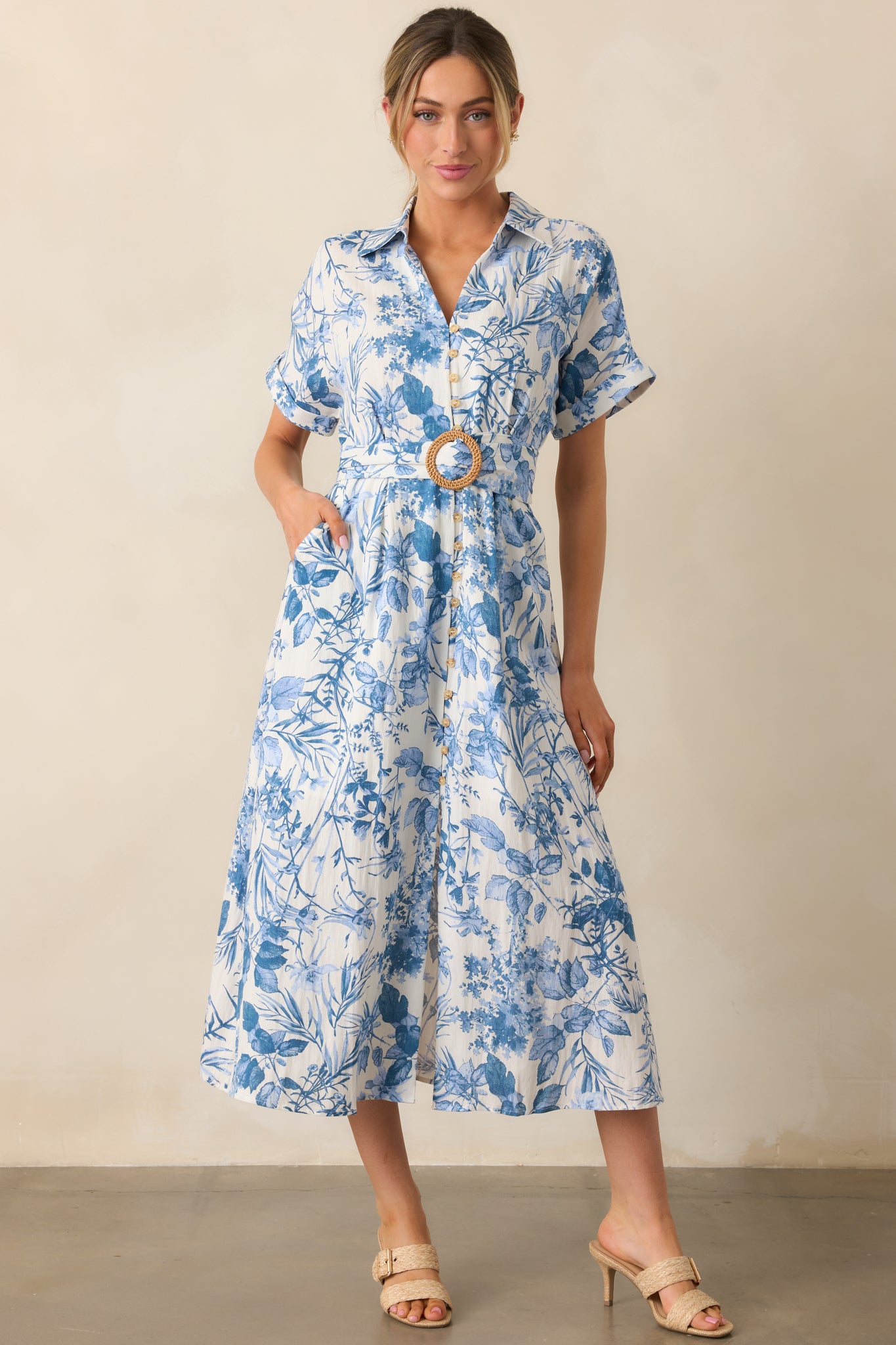 A midi dress with a collared V-neckline, functional button front, elastic waistband, pull-through belt, hip pockets, and cuffed short sleeves.