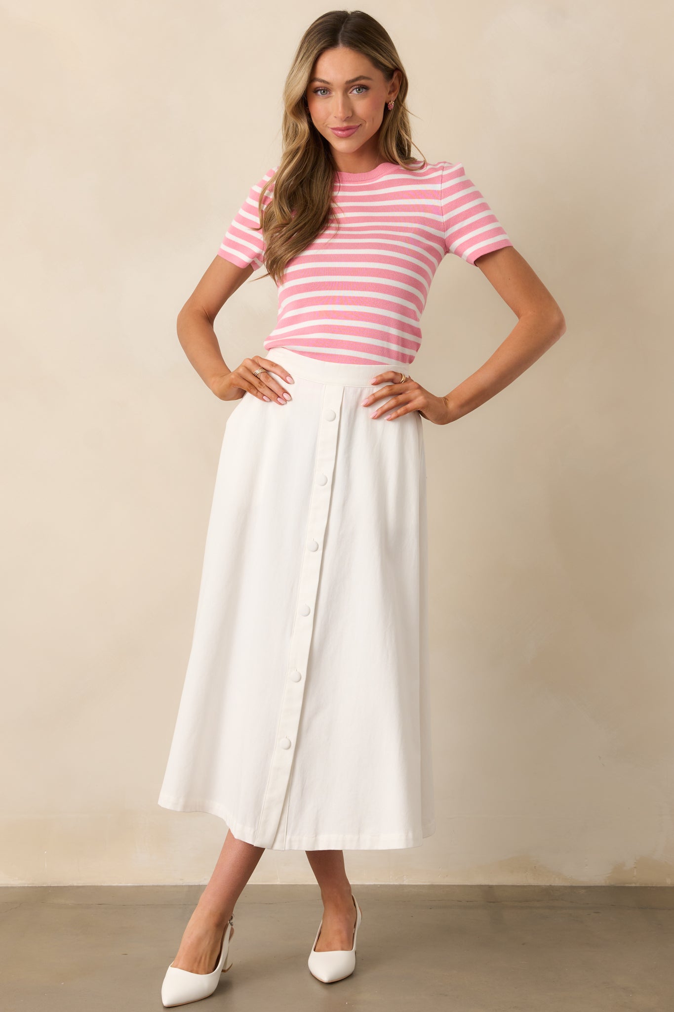 This elegant ivory midi skirt features a high-waisted fit, with the subtle sophistication of faux buttons down the front, offering a refined and timeless silhouette.