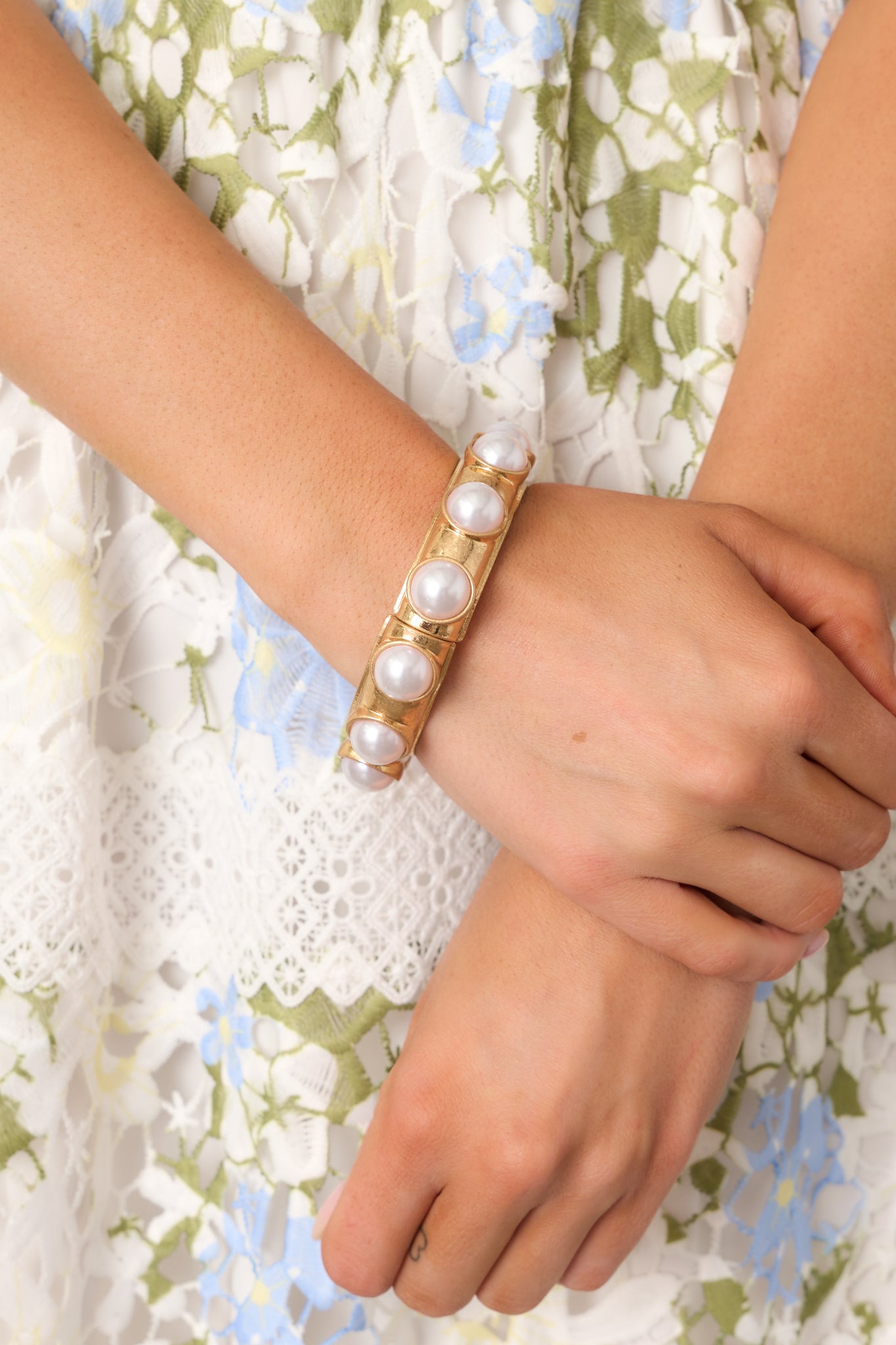 A close-up front view of the gold and ivory bracelet, showcasing the large faux pearls and gold hardware.