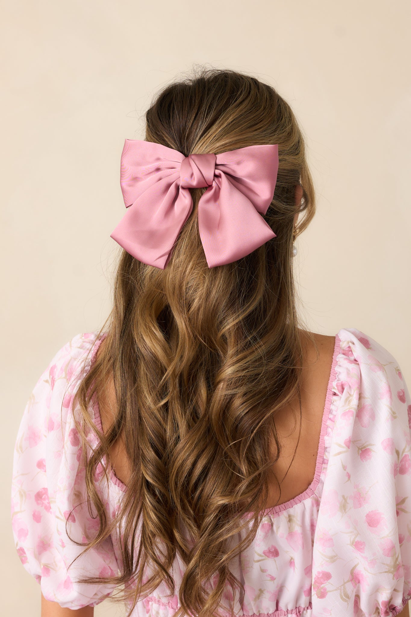 A classic pink bow hair clip with a structured shape and elegant design.