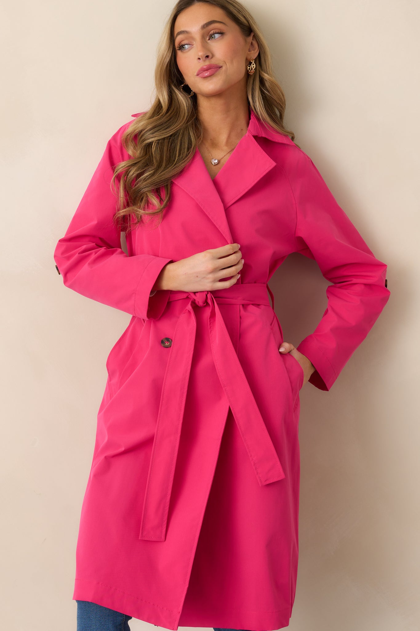 A close-up of the double-breasted lapels and functional button front, showcasing the tailored design of the magenta coat.