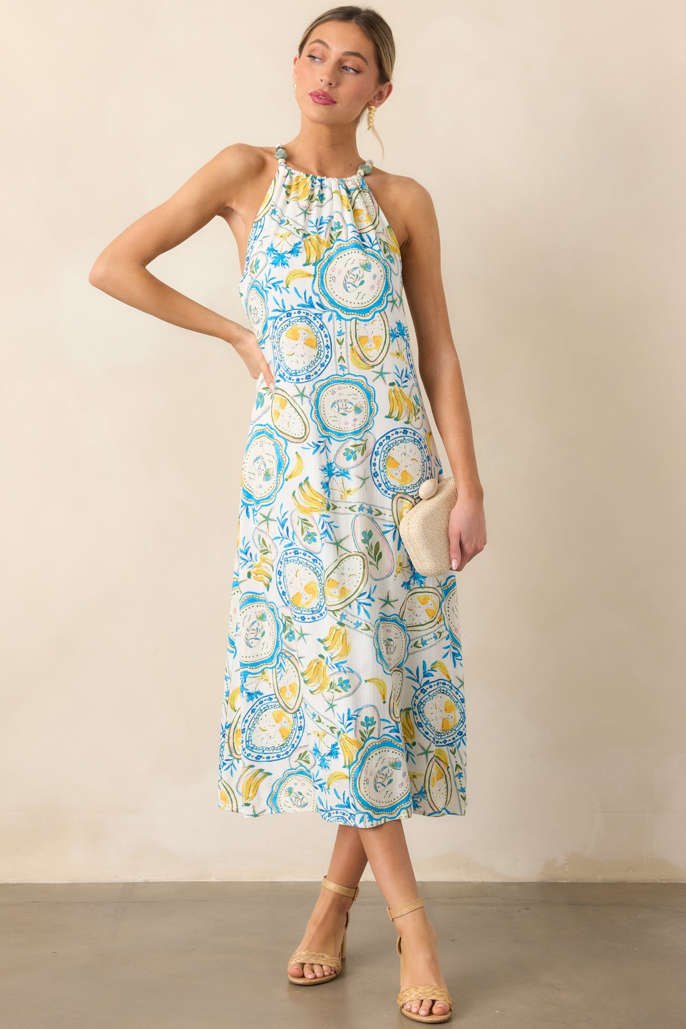 A front-facing view of the ivory midi dress, featuring a halter neckline, a blue and yellow tropical print, and a relaxed fit with a midi length.