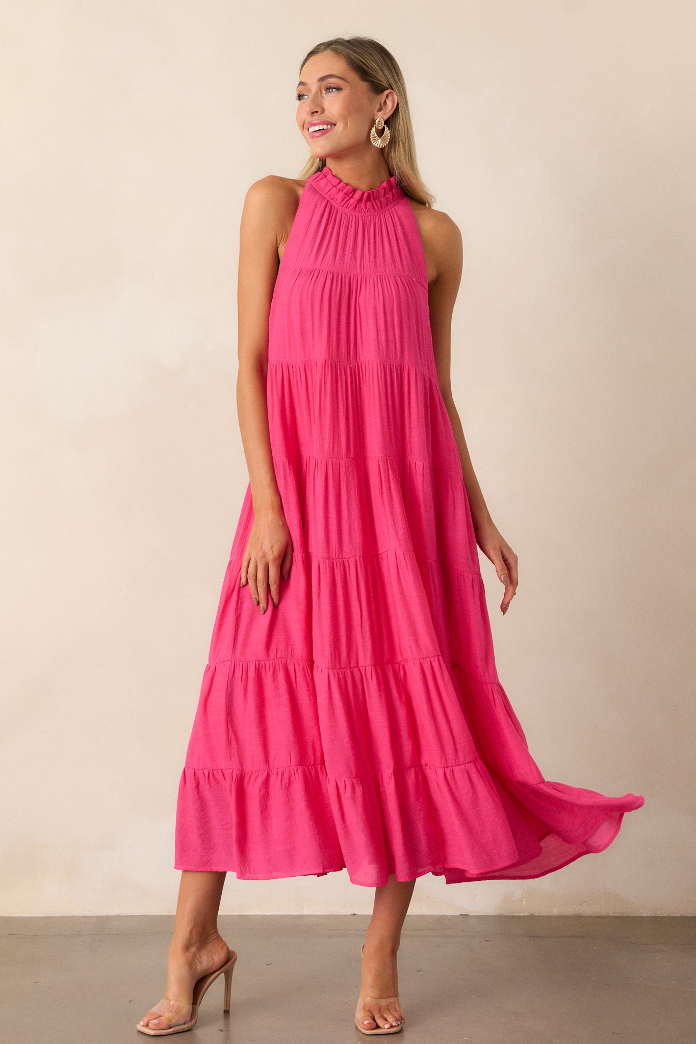 Full view of the hot pink dress showcasing its high neck design and ruffled collar, standing against a soft, neutral background.