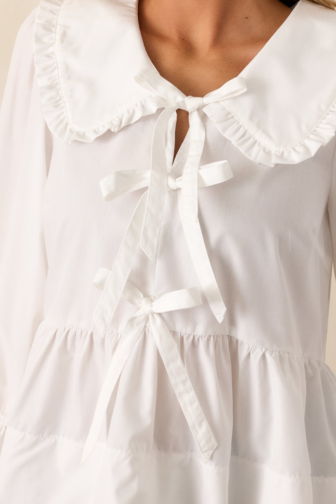 A detailed close-up of the blouse’s front, highlighting the intricate ruffled collar and bow accents.