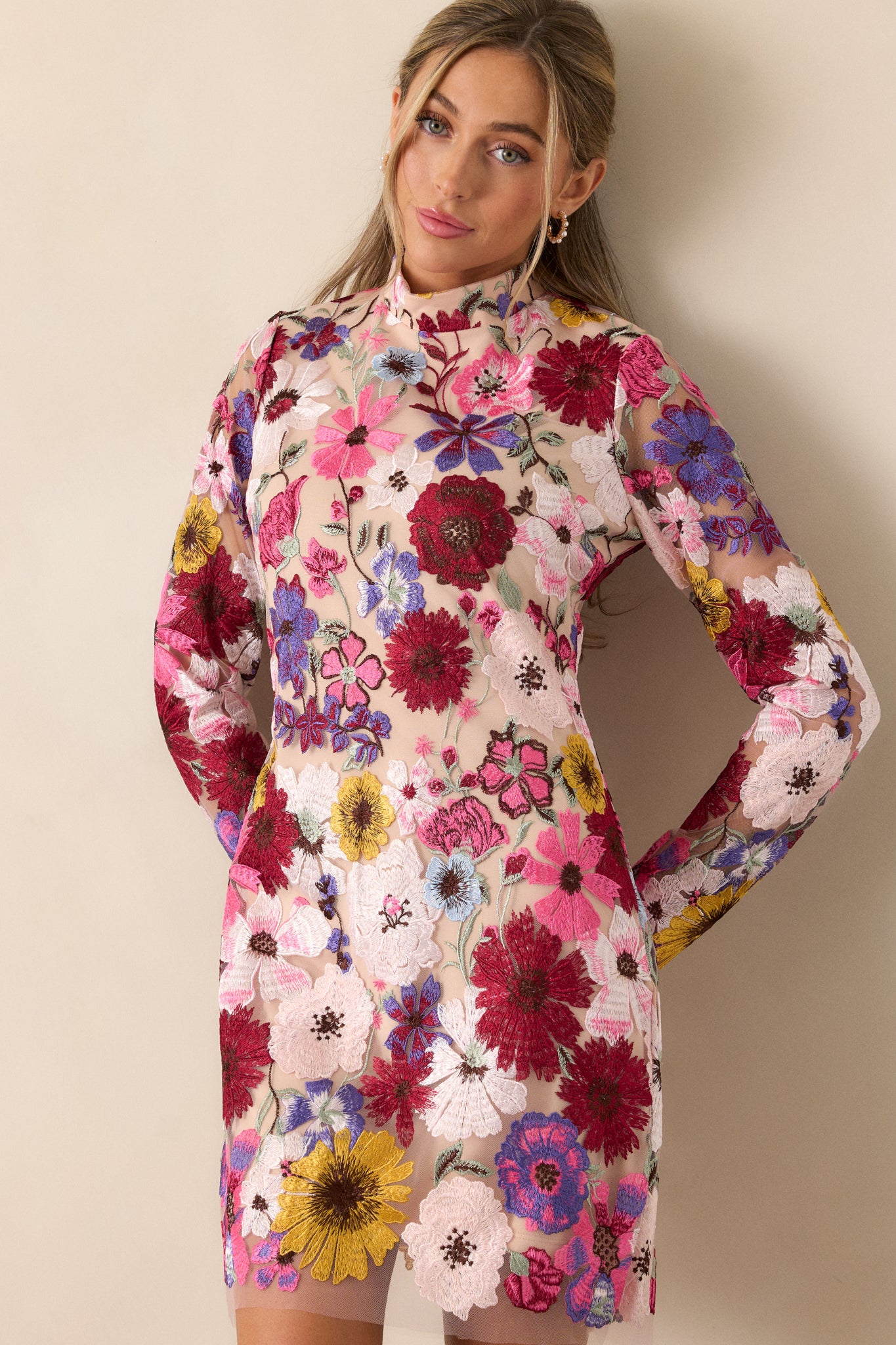 Full view of the mini dress with a high neckline, fitted design, and sheer floral overlay, showing the mini length and sheer long sleeves.