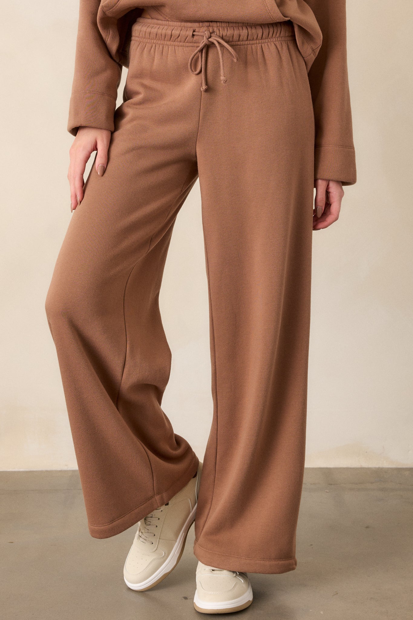 Close-up of the elastic waistband and adjustable drawstring of the brown sweatpants, showing their functional design.