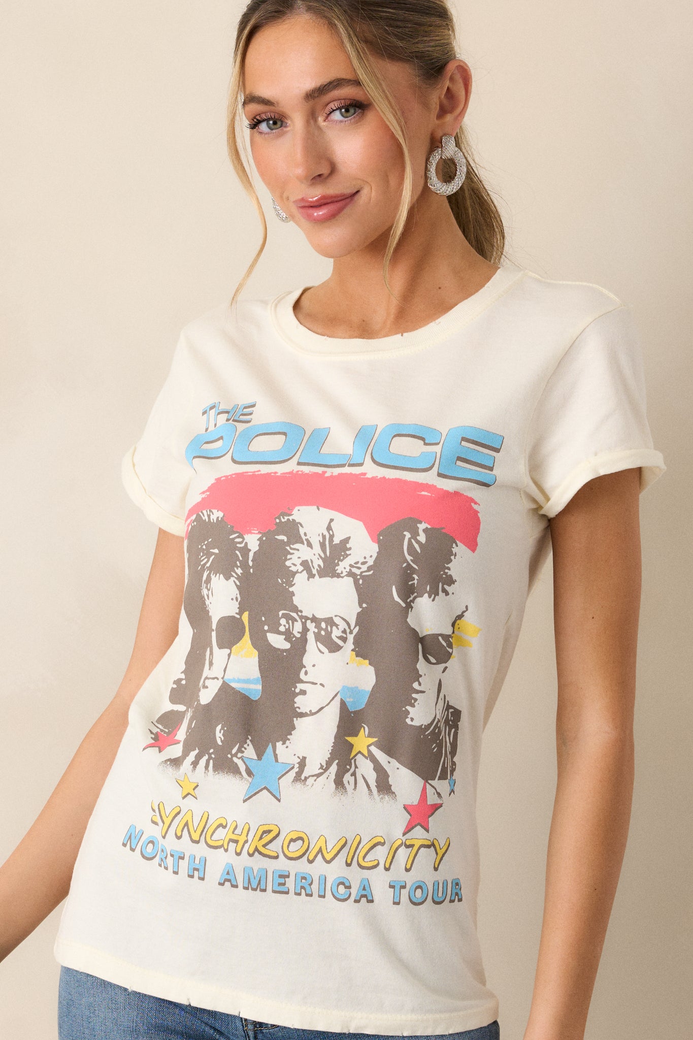 A cropped shot emphasizing the round neckline and cuffed sleeves of the ivory tee. The "The Police Synchronicity North America Tour" graphic is positioned in the center of the chest.