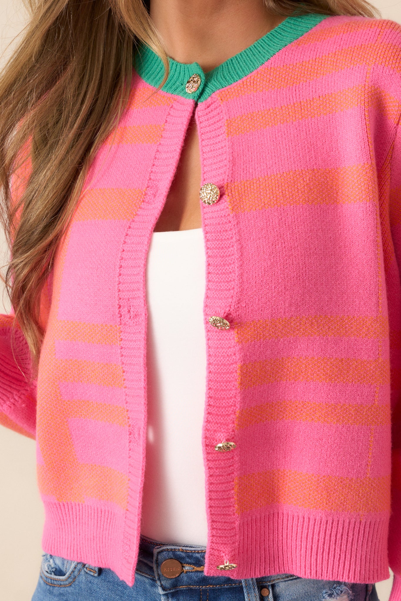 Close-up of the orange stripe detailing on the pink cardigan, highlighting the vibrant contrast with the pink and green design.