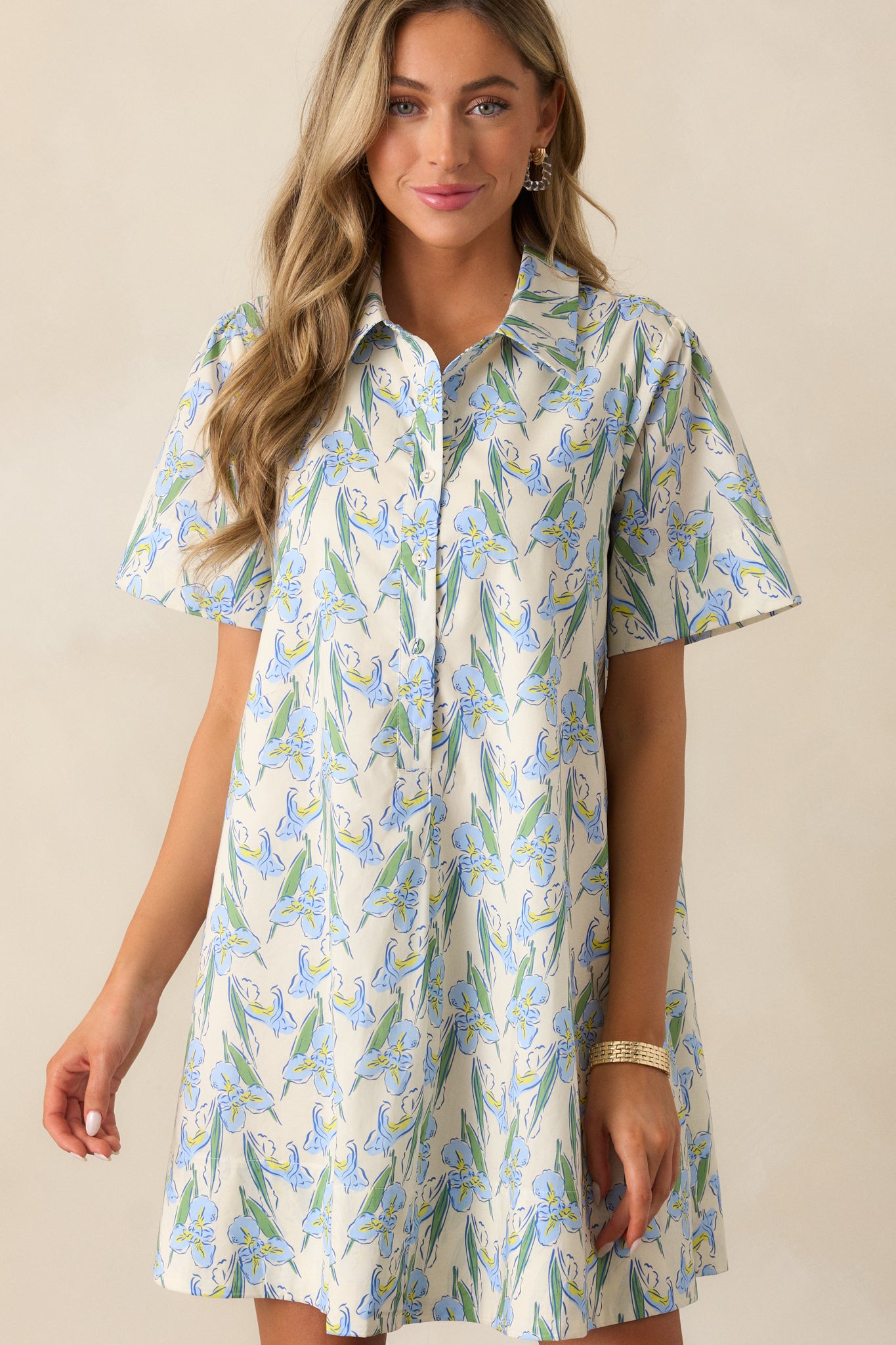 A blue dress with a collared v-neckline, functional buttons, and a relaxed fit, adorned with a beautiful floral print that adds charm.