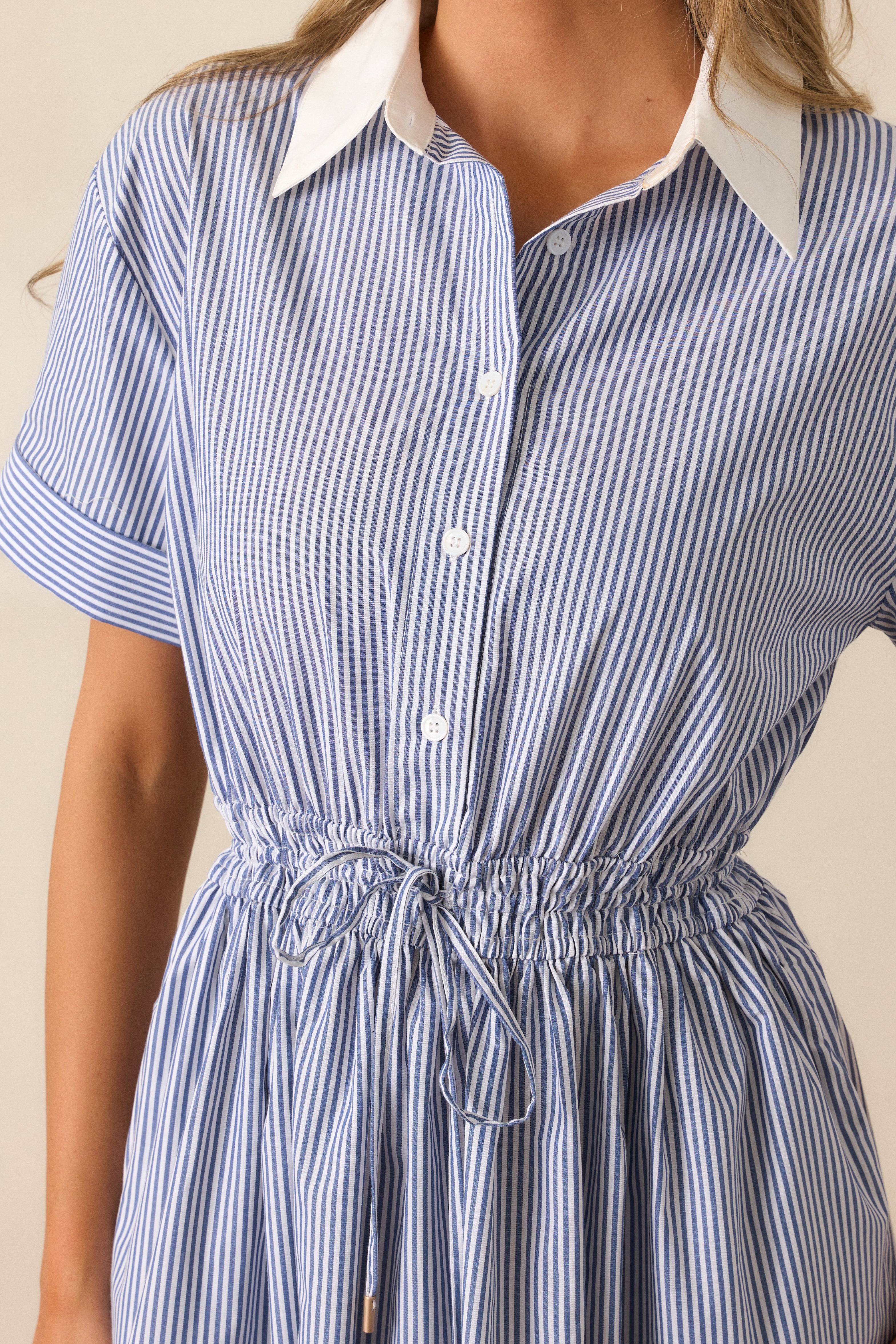 Close-up of the white collared neckline and short cuffed sleeves of the blue dress, highlighting the fine stitching and clean edges.