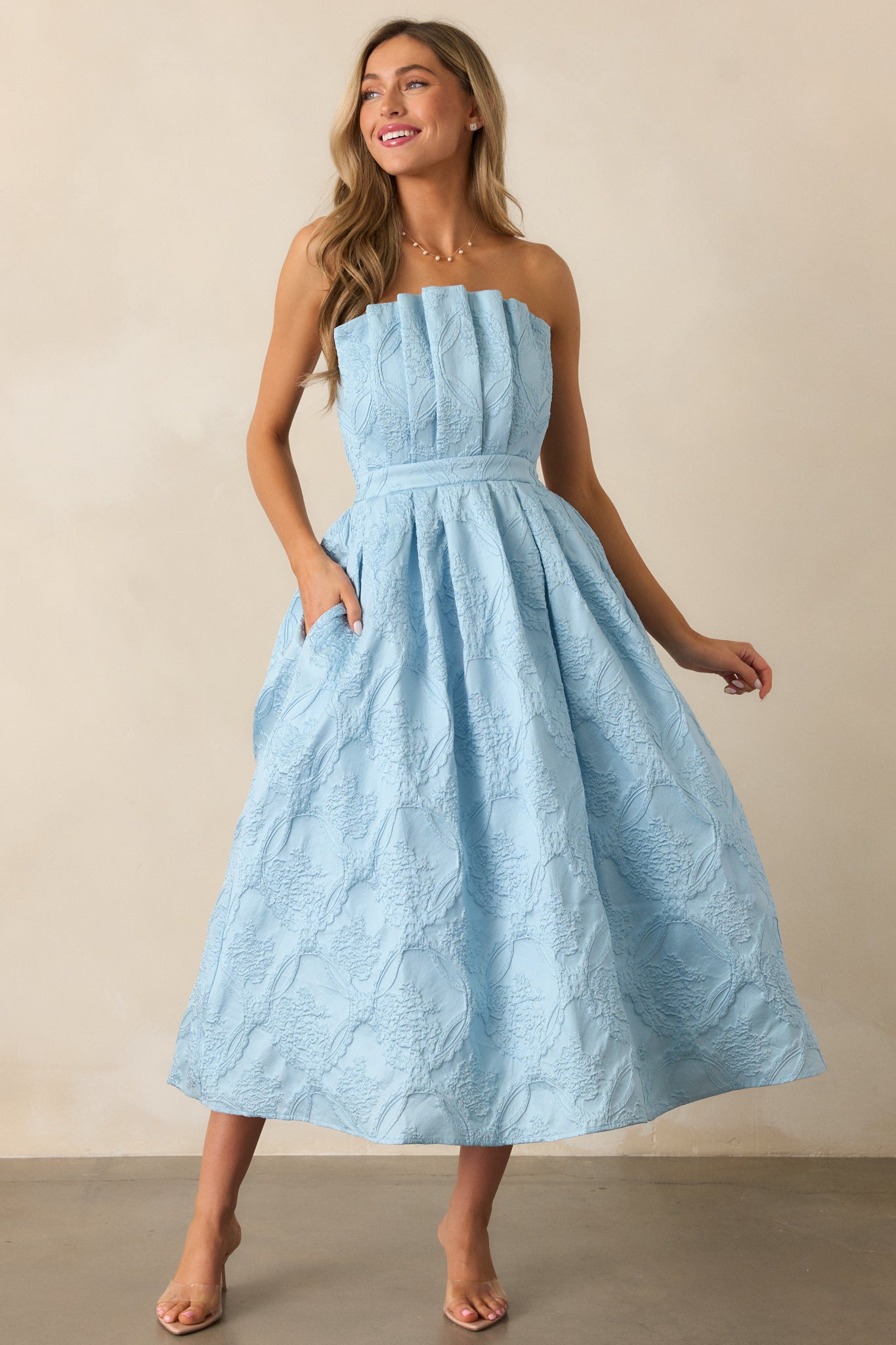  A sky blue midi dress featuring a strapless design, pleated bodice, and slightly pleated skirt with a jacquard pattern.