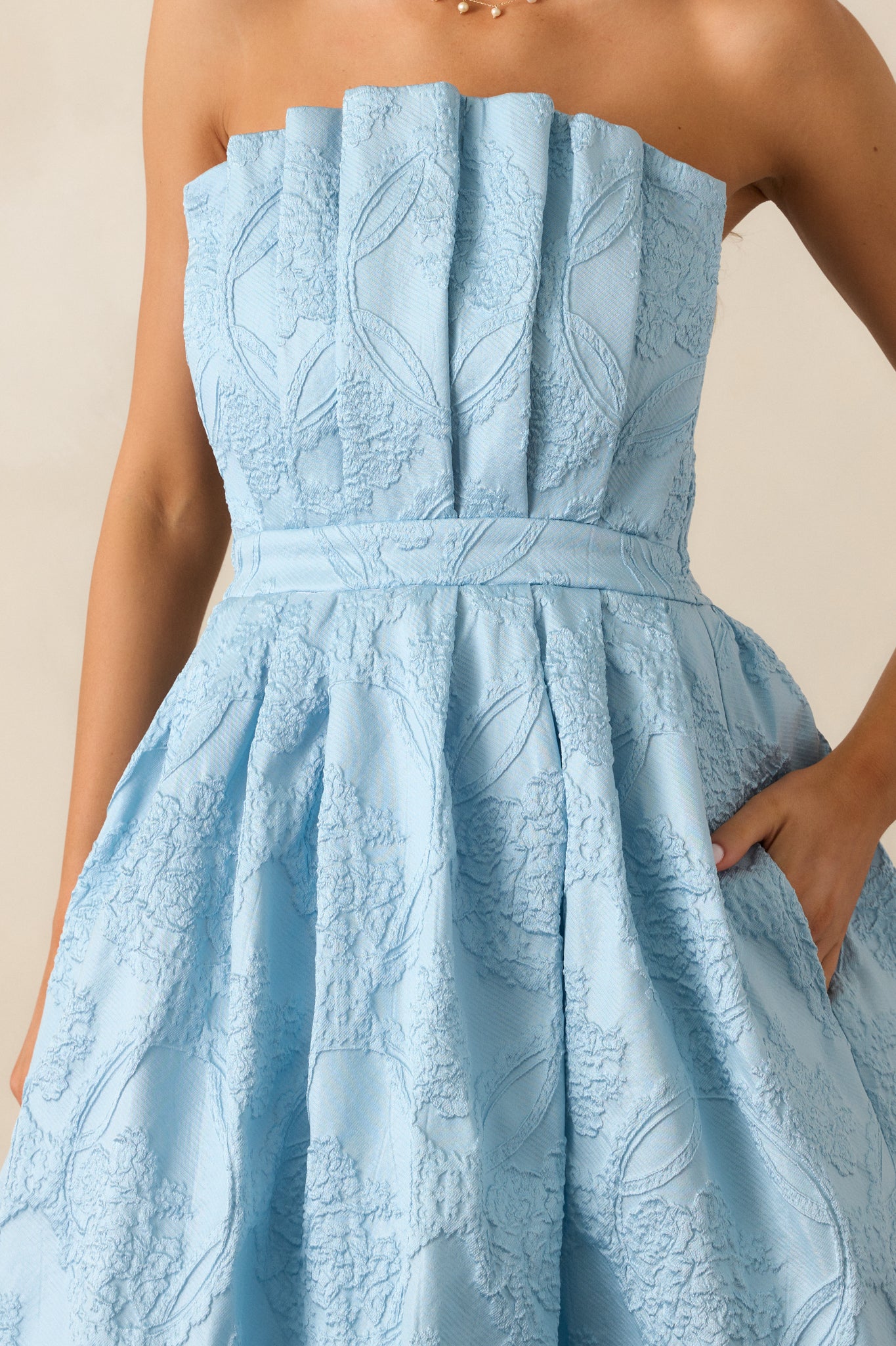 A close-up of the pleated bodice and jacquard design of the sky blue midi dress, showcasing the intricate texture and structure.