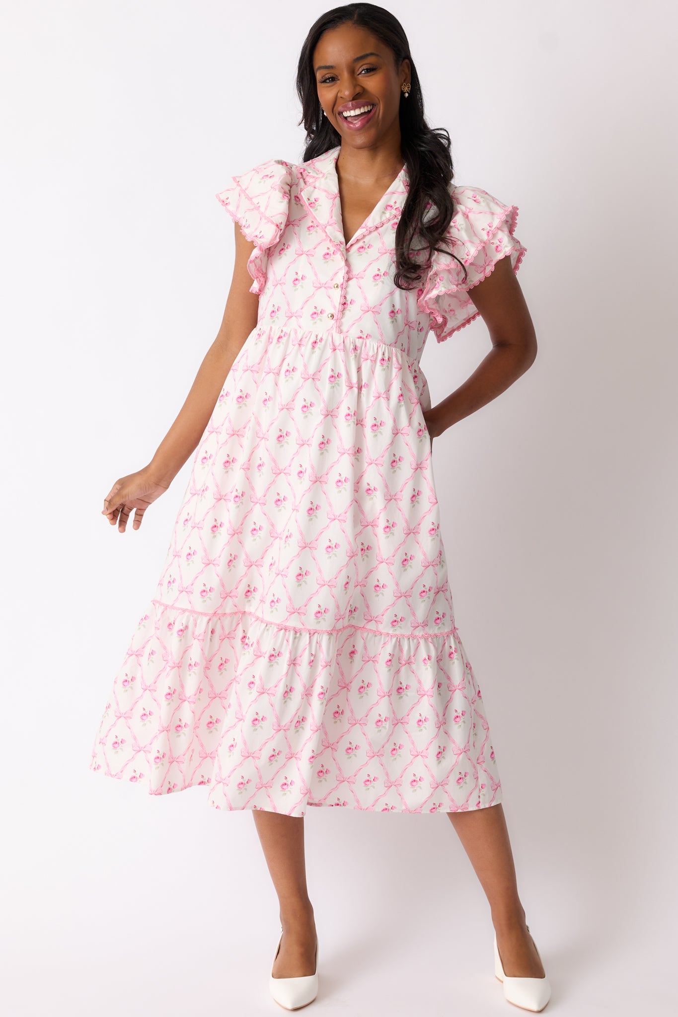 A front view of the light pink dress highlighting its collared neckline, button-front detailing, and flutter sleeves.