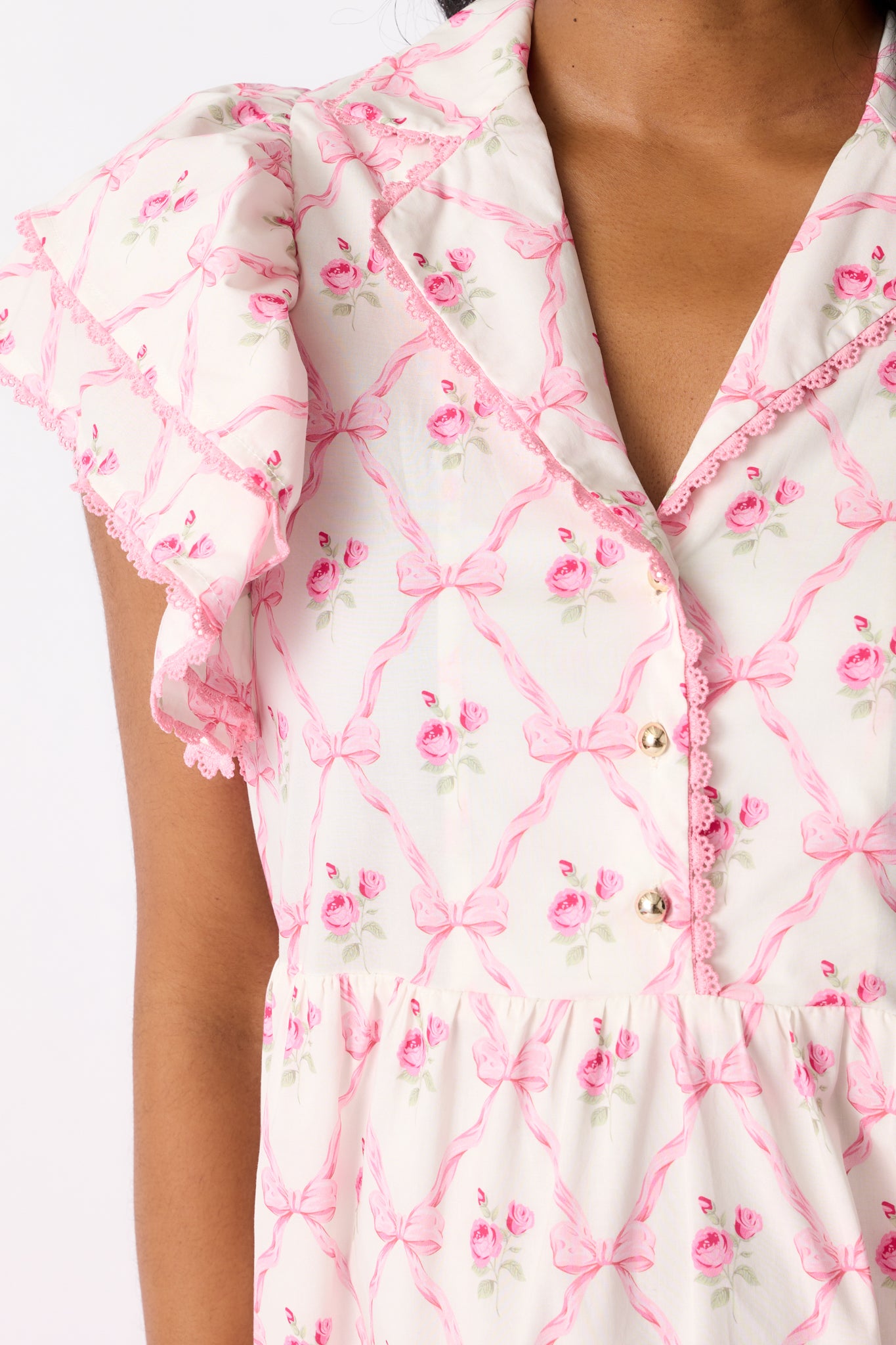 A zoomed-in shot of the floral bow pattern and pink trim on the dress, emphasizing the delicate design details.