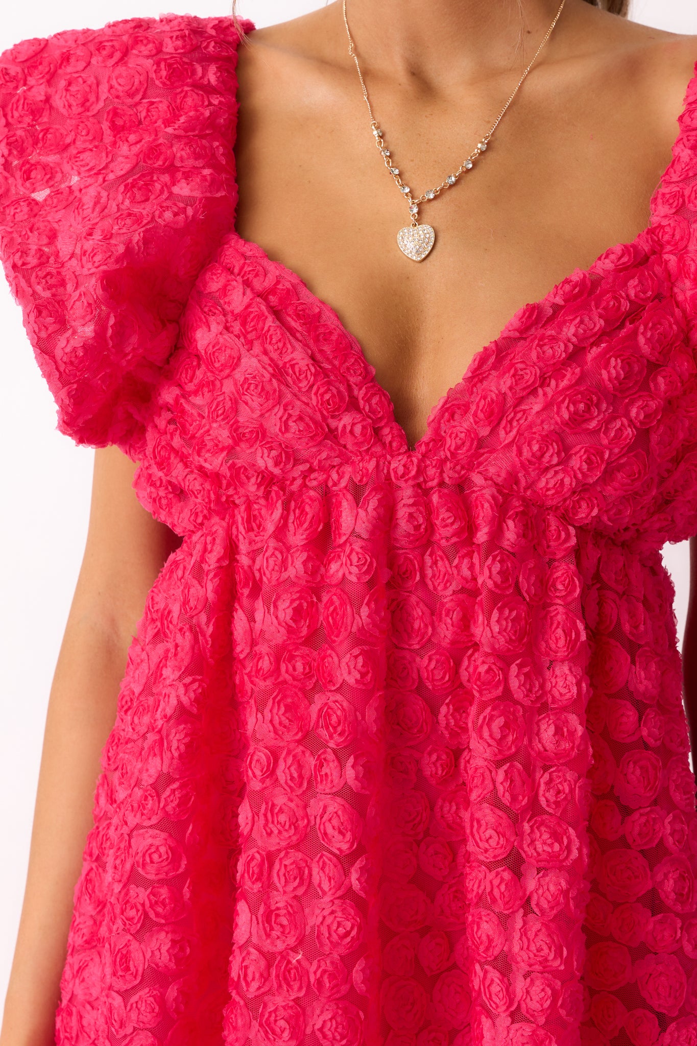 A zoomed-in shot of the rose embroidery on the fabric, emphasizing the intricate texture and vibrant hot pink hue.