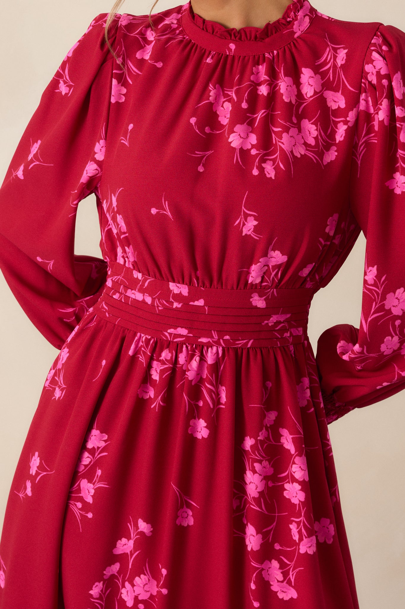 A close-up of the floral pattern and the tiered bottom detailing of the pink and red dress, highlighting the fabric and its intricate design.