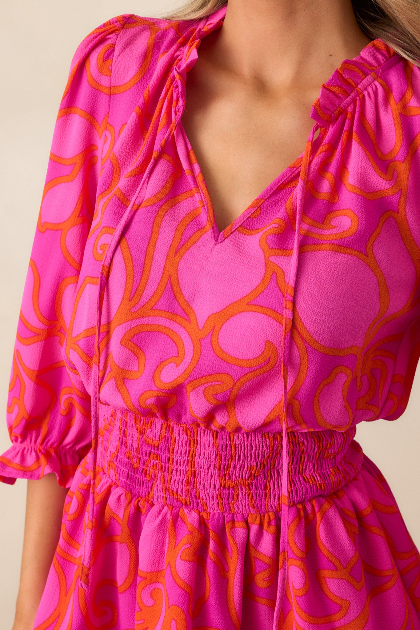 Close-up of the orange floral detailing on the magenta mini dress, showcasing the vibrant print and the delicate texture of the fabric.