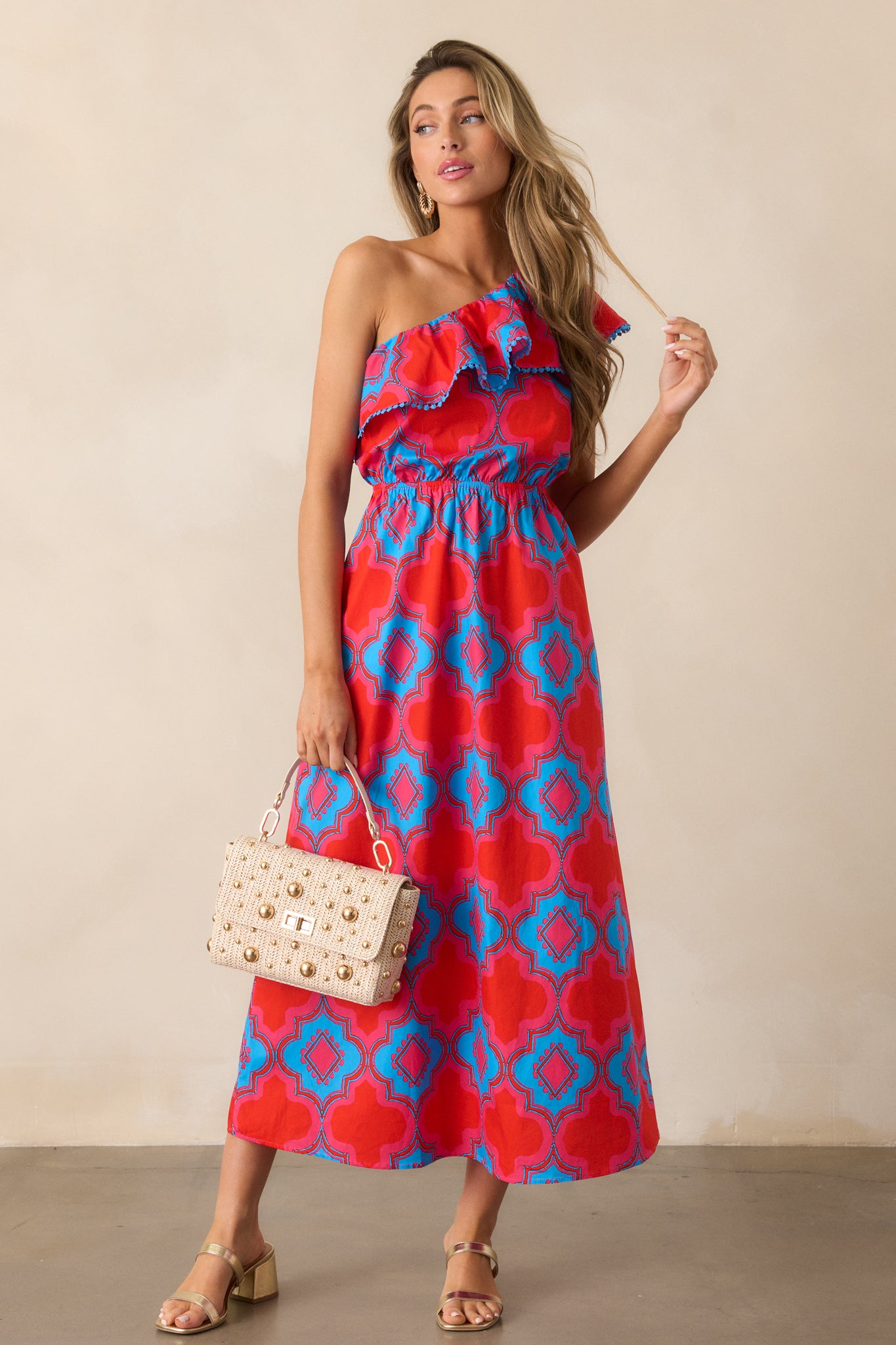 Full-length image of the red dress, highlighting the elastic waistband and the vibrant blue and pink print across the fabric.