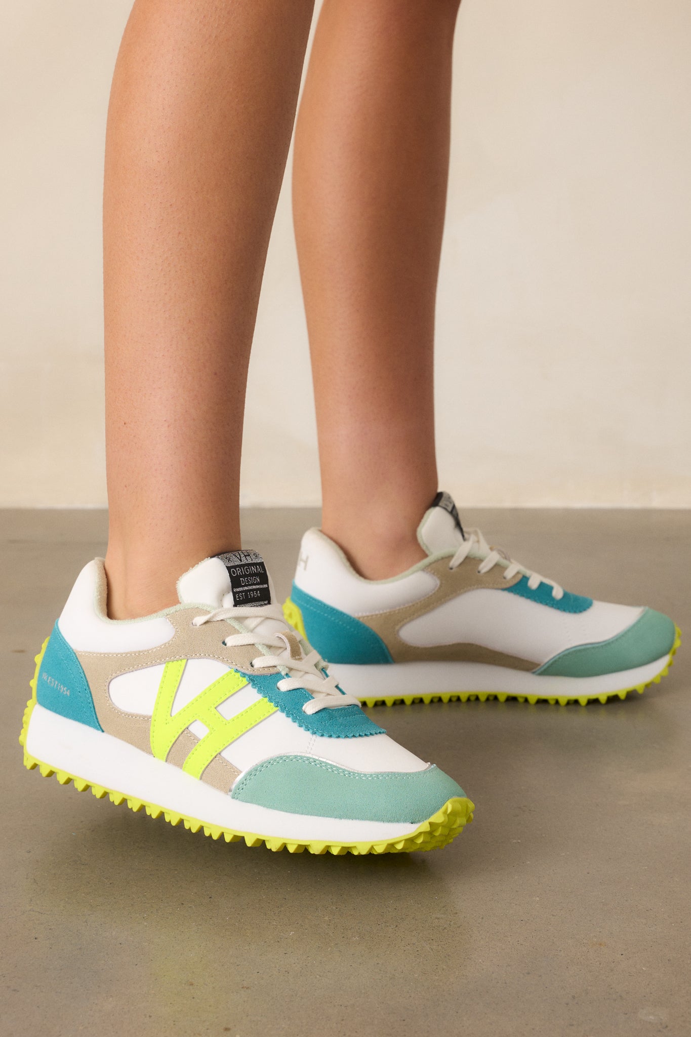 A side view of the neon yellow sneakers showcasing their rounded toe, functional laces, and slight platform against a beige background.