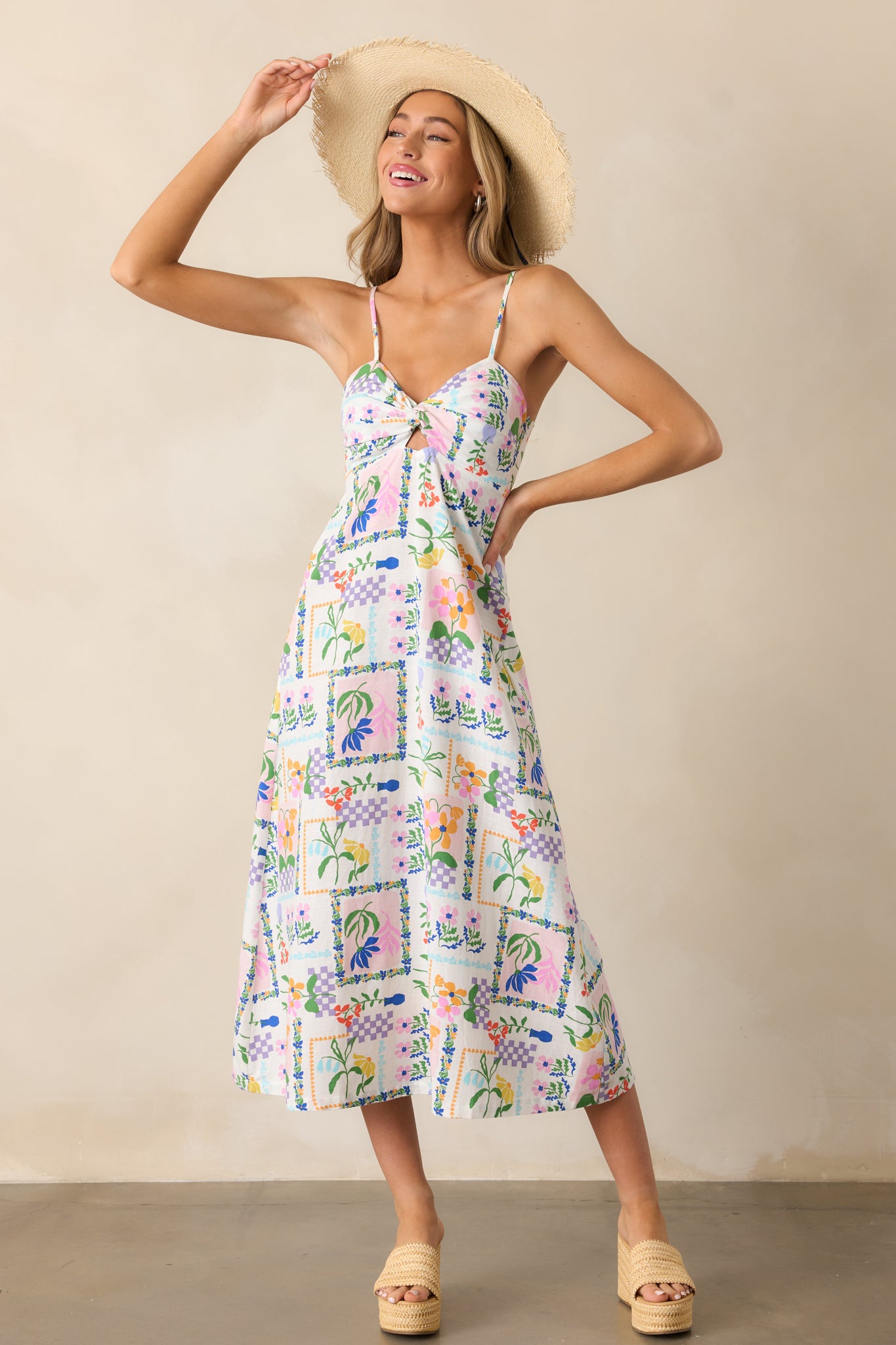 A full view of the ivory dress showcasing its twist neckline with cutout detailing, colorful picnic pattern, and relaxed fit.