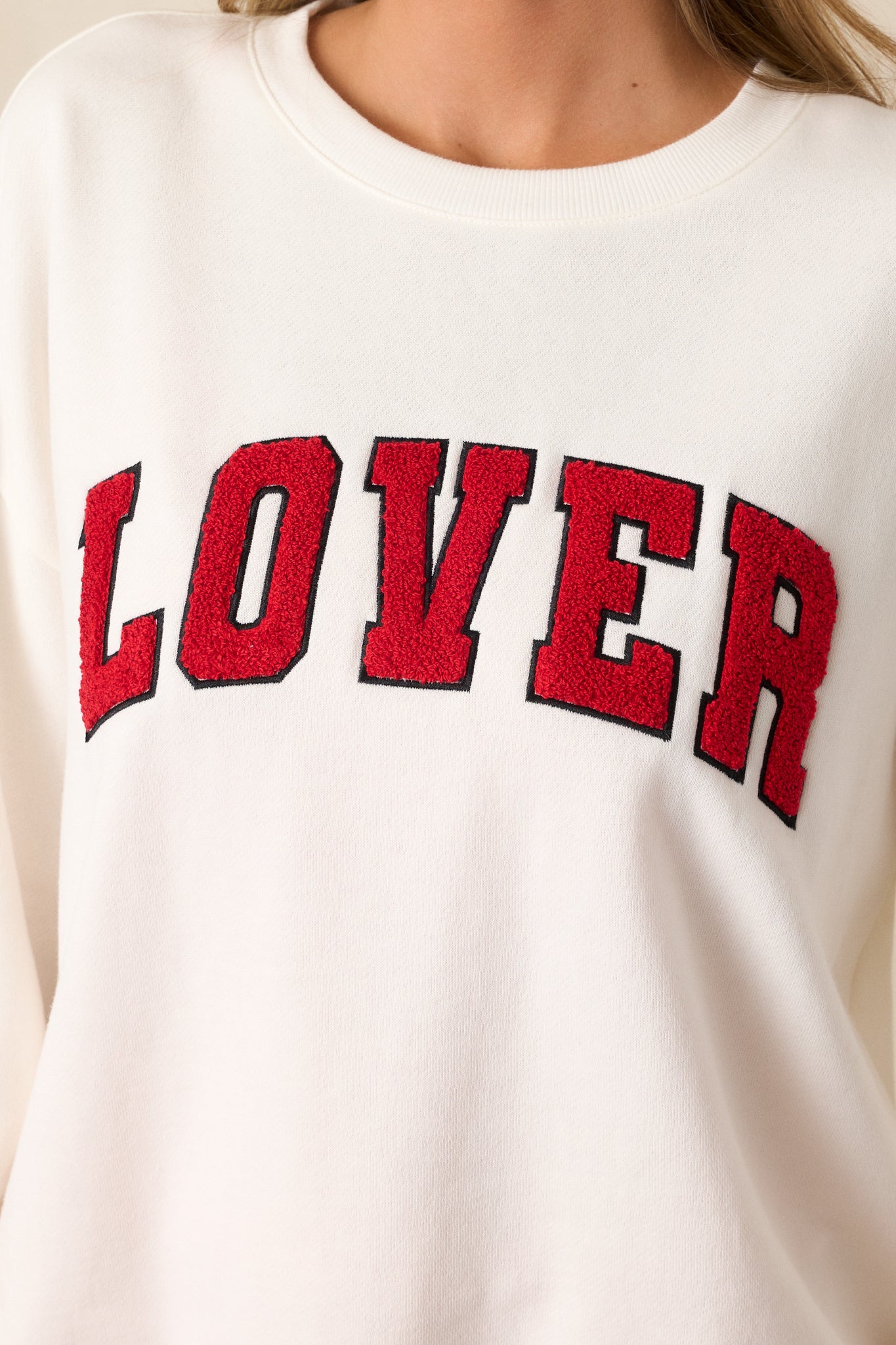 A detailed shot of the red "LOVER" script, highlighting the textured lettering on the ivory fabric, with emphasis on the fabric’s weave and texture.