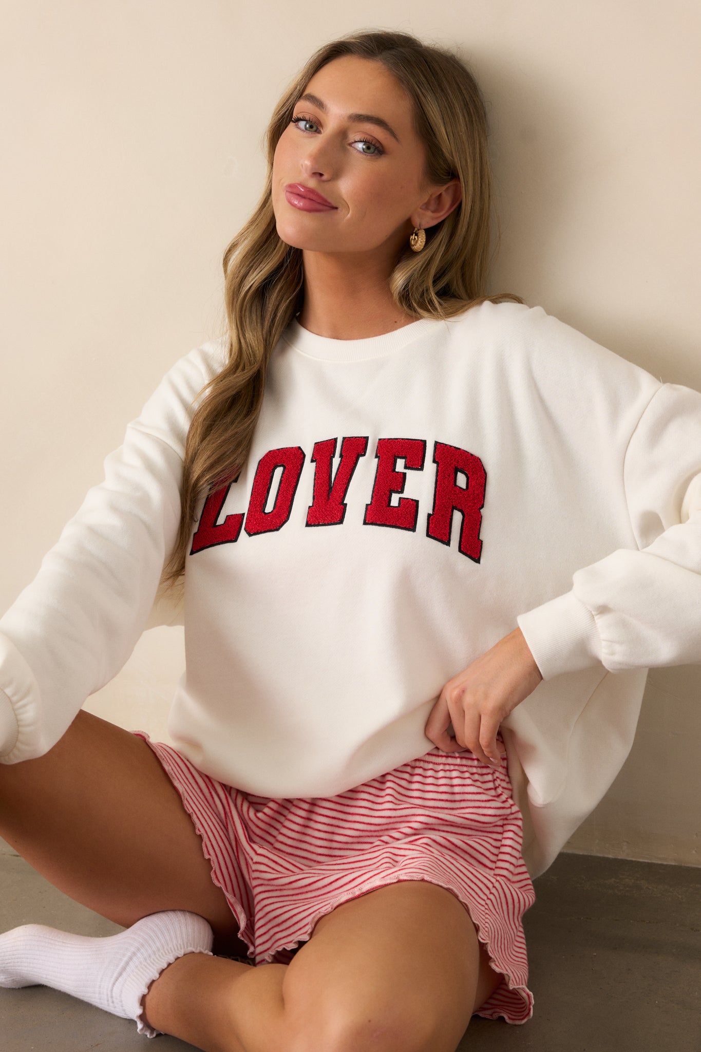 A cropped view emphasizing the ribbed cuffs on the sleeves and the relaxed fit of the sweatshirt, with the red "LOVER" script visible in the center.