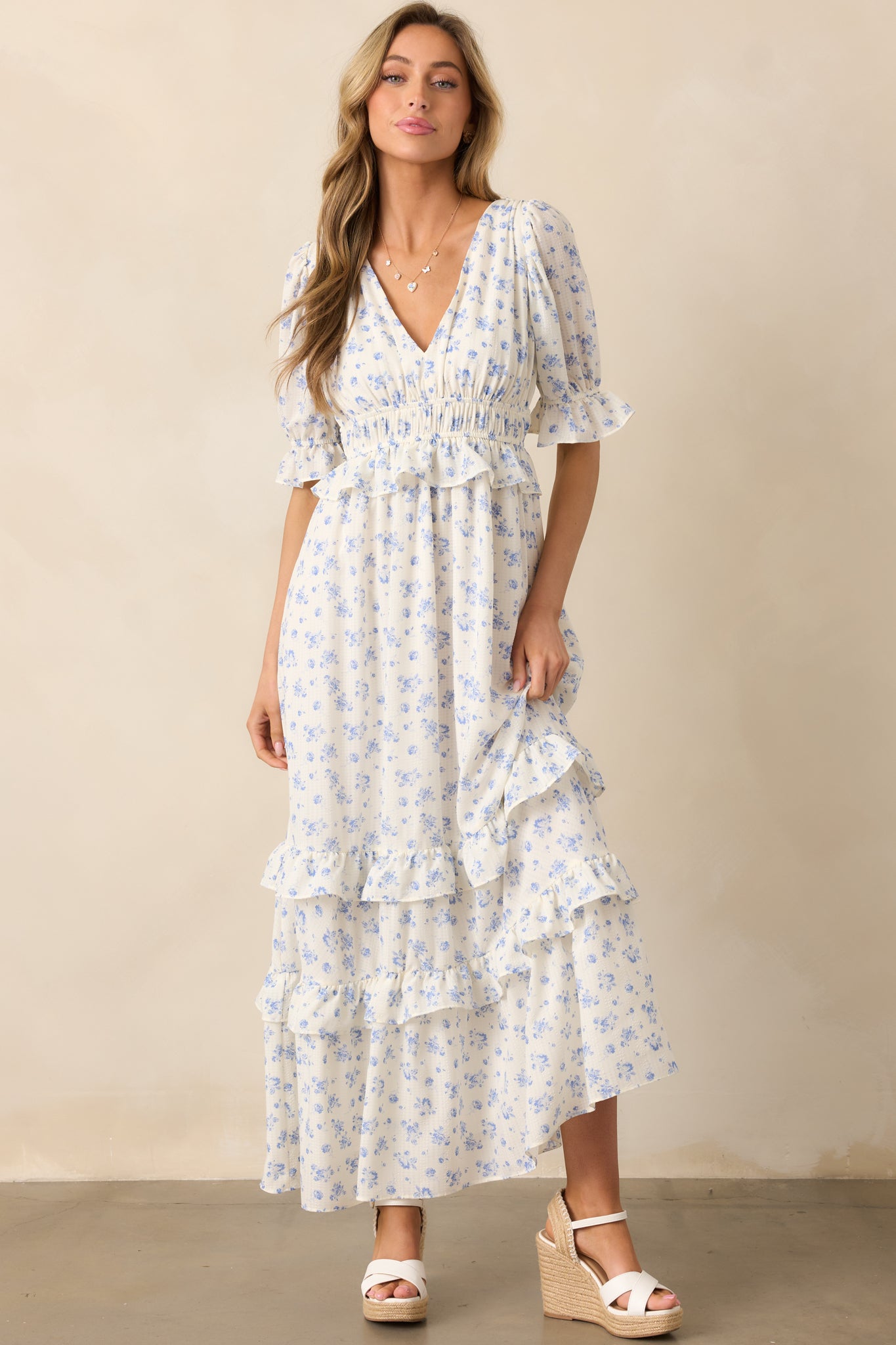 An ivory dress featuring a blue floral pattern, a v-neck neckline, and delicate ruffle detailing for a soft, romantic look.