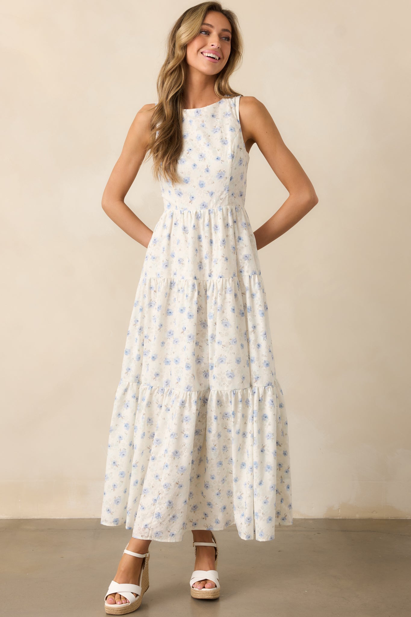 An ivory dress featuring a blue floral pattern, a round neckline, and a three-tiered design for a flowy, feminine silhouette.