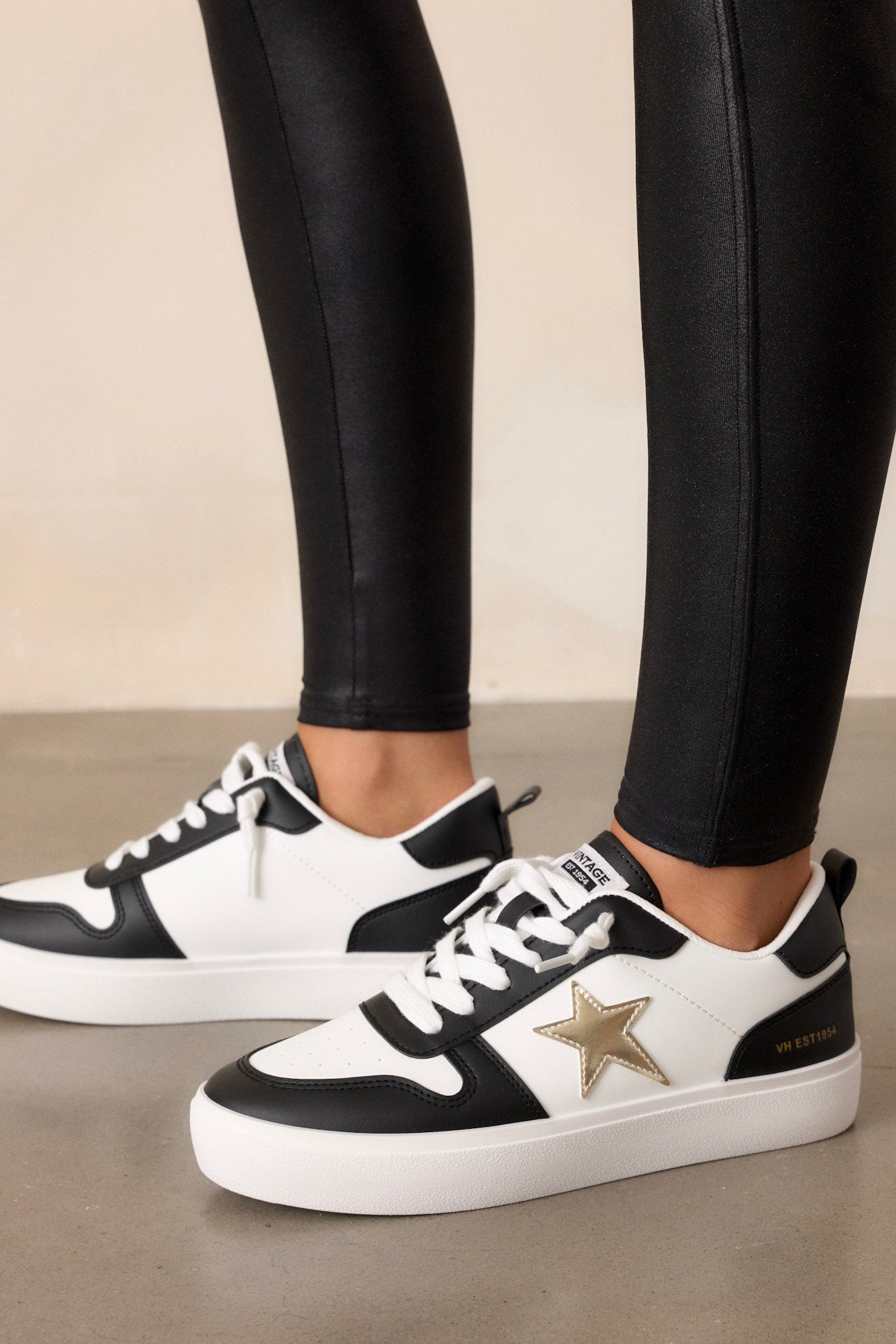 These black sneakers feature a rounded toe, functional white laces, interchangeable gold laces, a comfortable fit, a gold star detailing, and a thick sole.