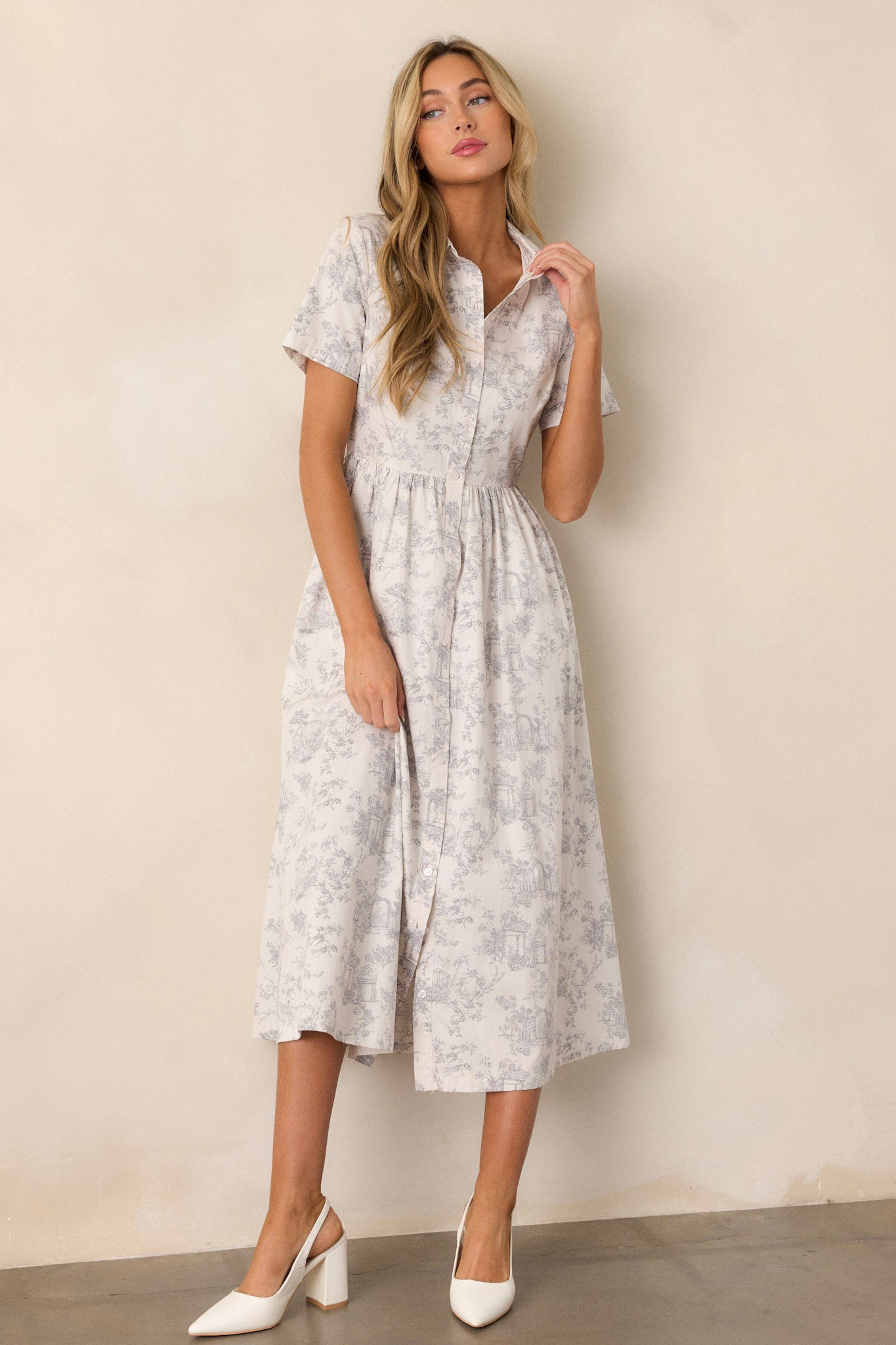 This light grey maxi dress features a collared neckline, a functional button front, gathering at the waist, functional hip pockets, a gorgeous toile pattern, and a flowing silhouette.