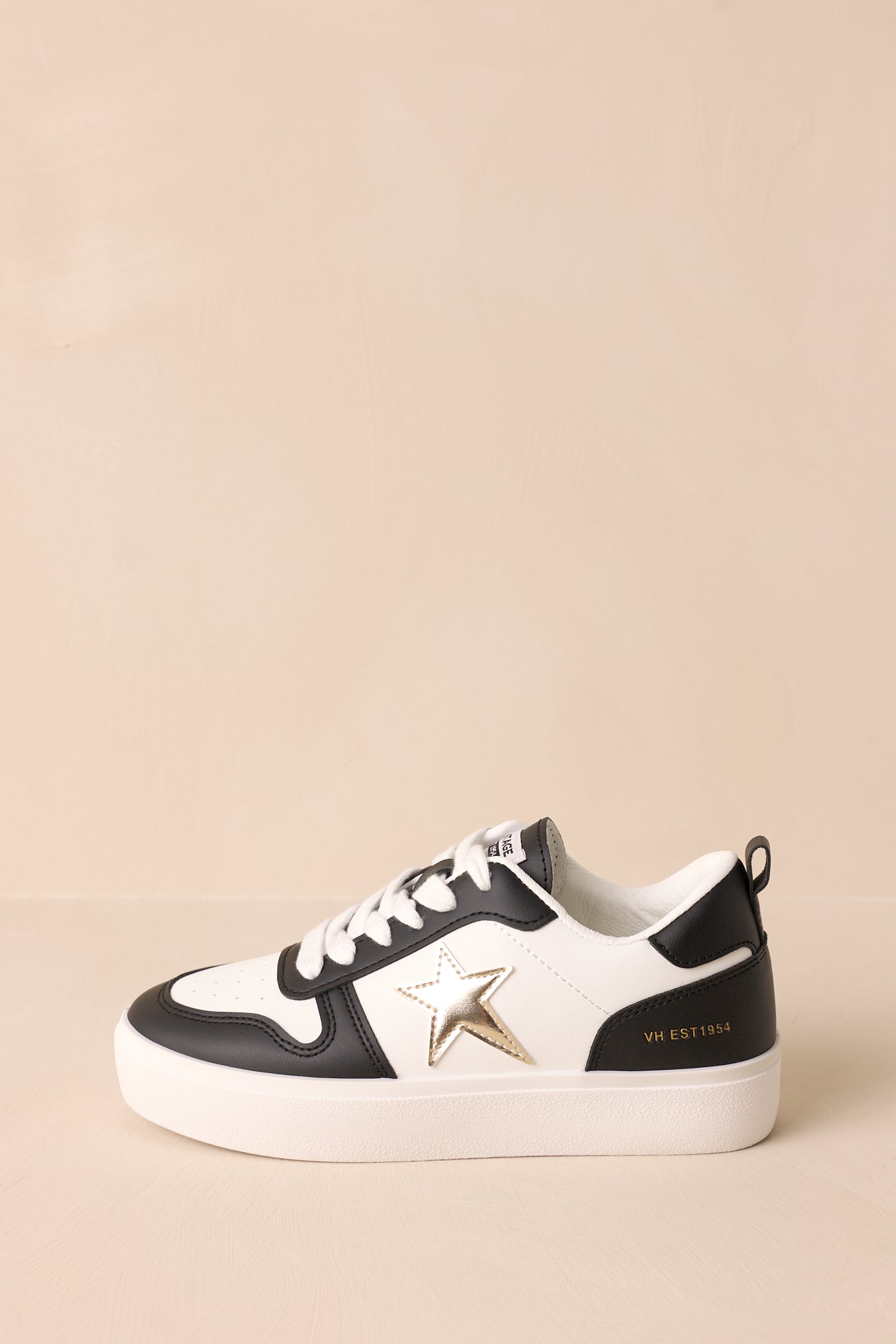 Side view of these black sneakers that feature a rounded toe, functional white laces, interchangeable gold laces, a comfortable fit, a gold star detailing, and a thick sole.