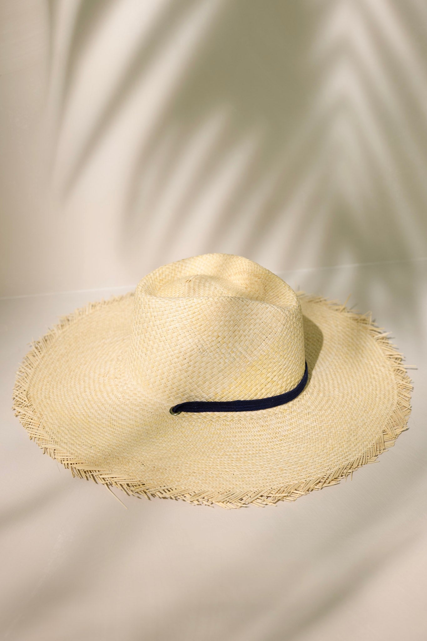 Full view of this Miriam hat features features a cotton navy band with a self-tie feature, and a fringed wide brim.